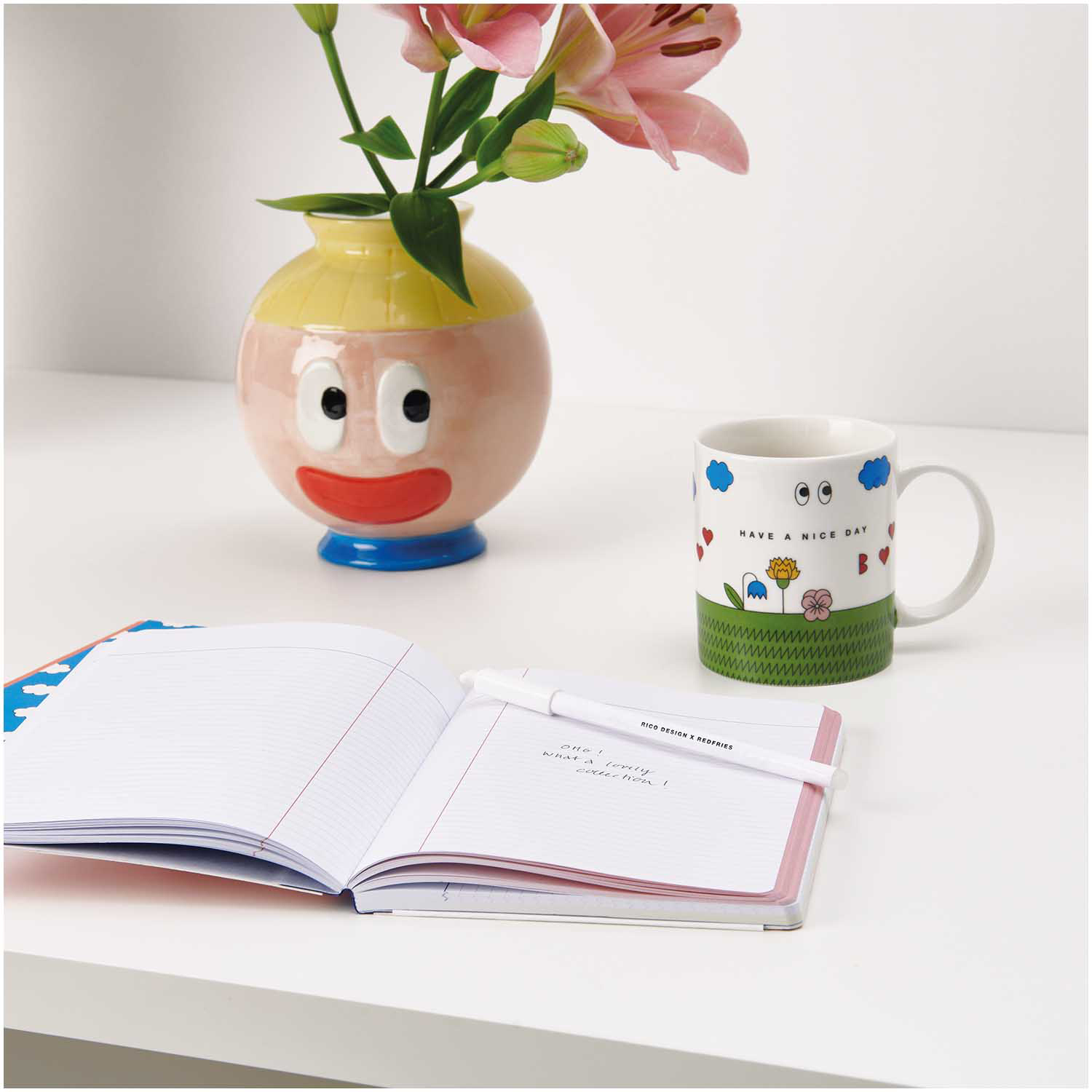 Rico Design x Redfries Keramik Vase Eye Candy mit frischen Blumen neben einer Tasse und einem Notizbuch auf einem Tisch.