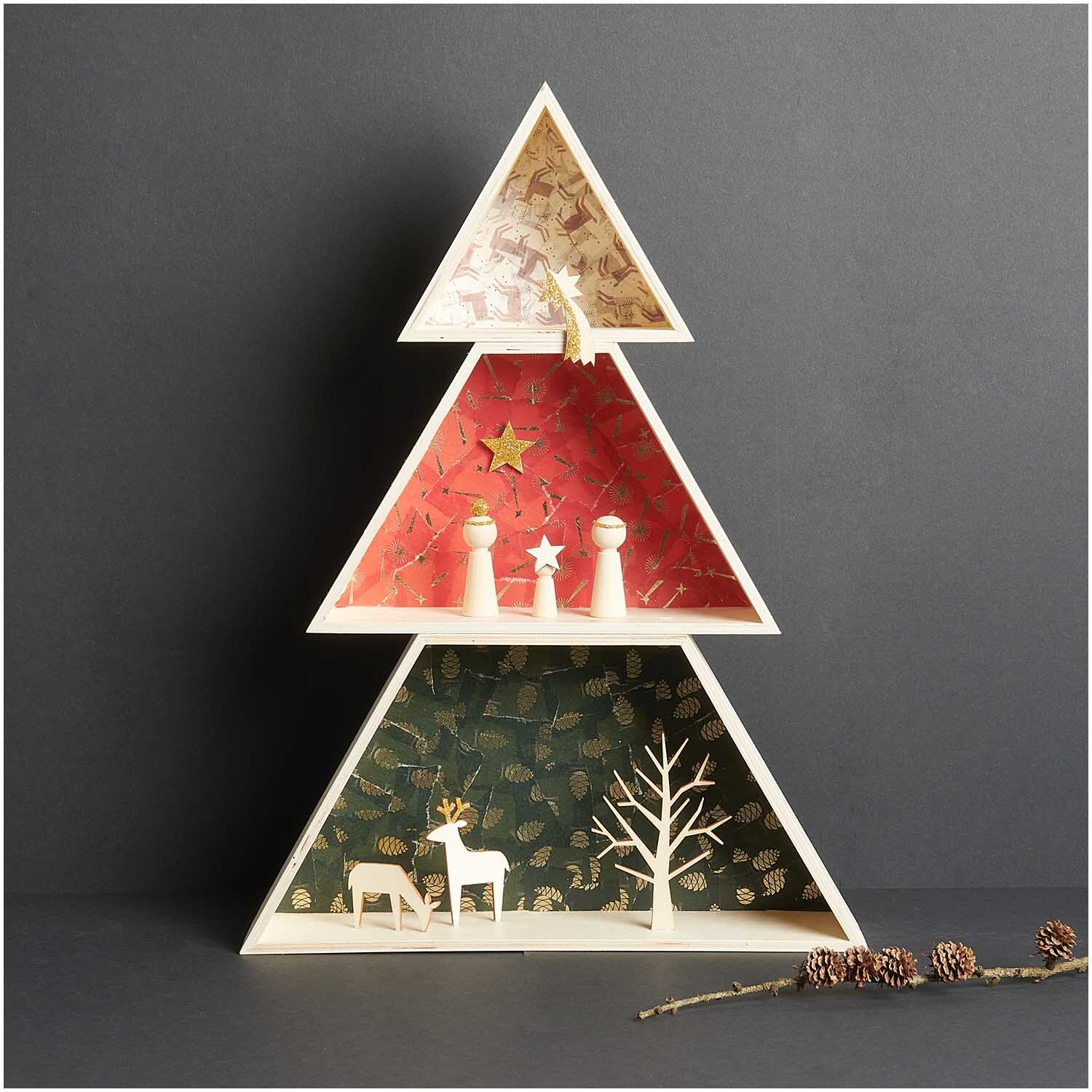 Paper Poetry Paper Patch Papier Tannenzapfen 30x42cm zeigt ein dreieckiges Regal in Form eines Weihnachtsbaums mit festlicher Dekoration.