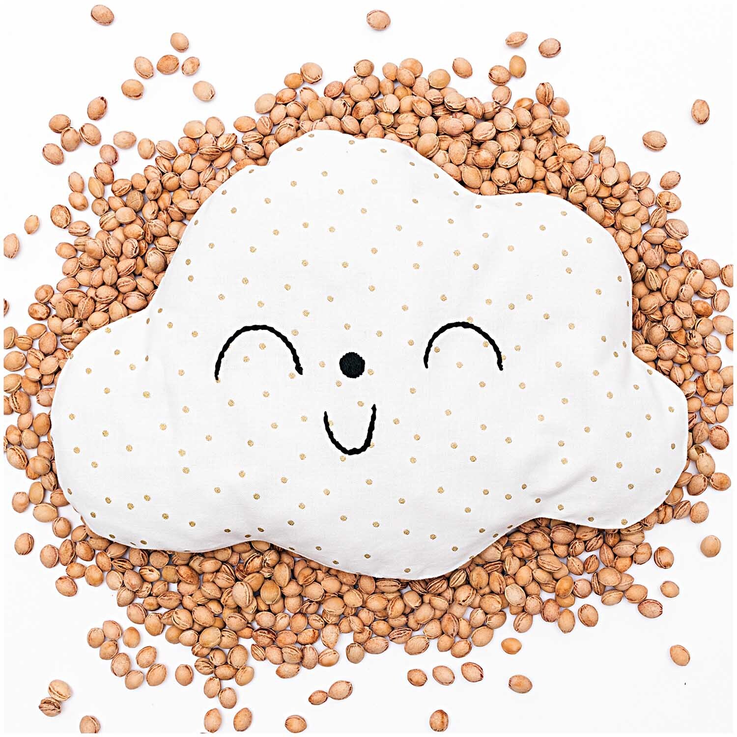 Kirschkerne 500g: Ein lächelndes Wolkenkissen liegt auf einer Schicht natürlicher Kirschkerne.