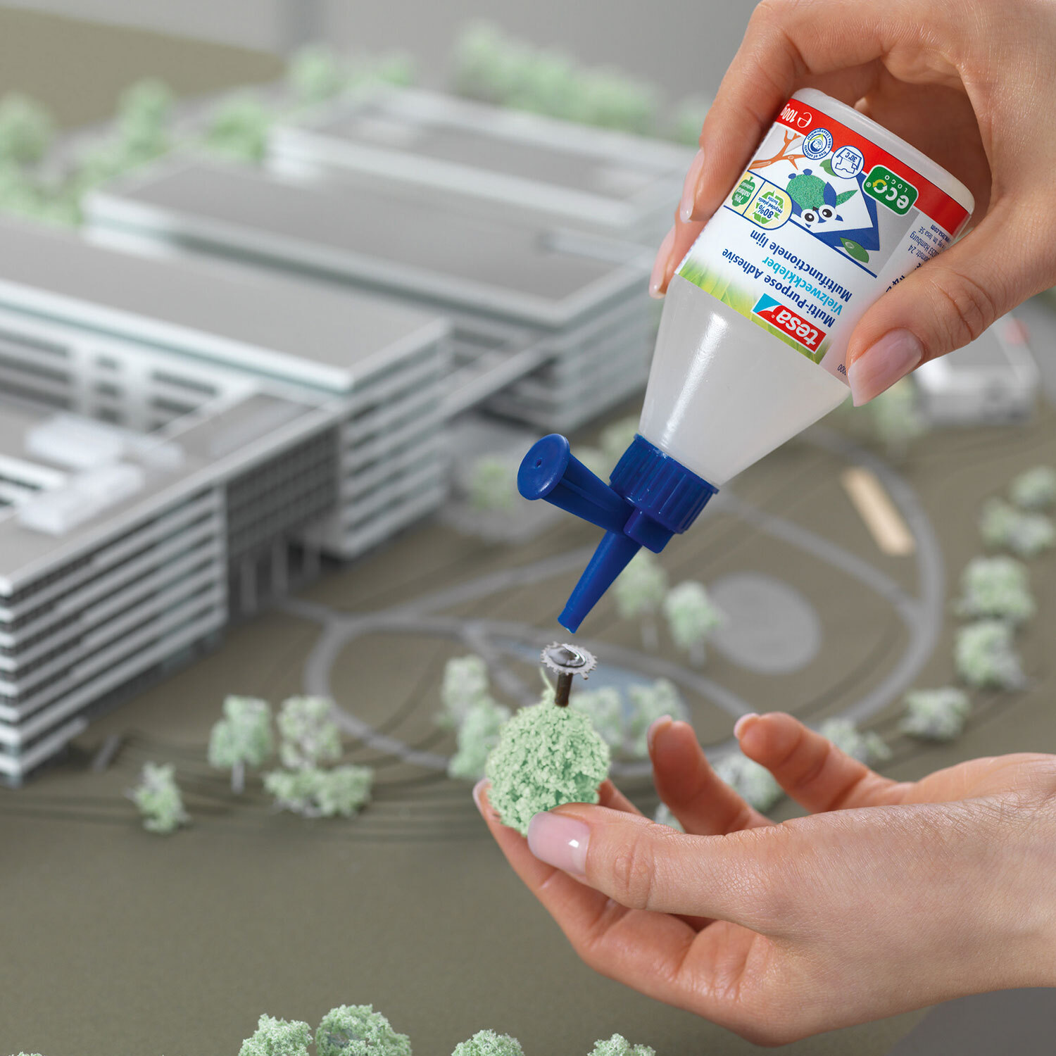 Vielzweckkleber 100g von tesa wird auf ein Miniaturmodell aufgetragen, um Bäume zu befestigen.