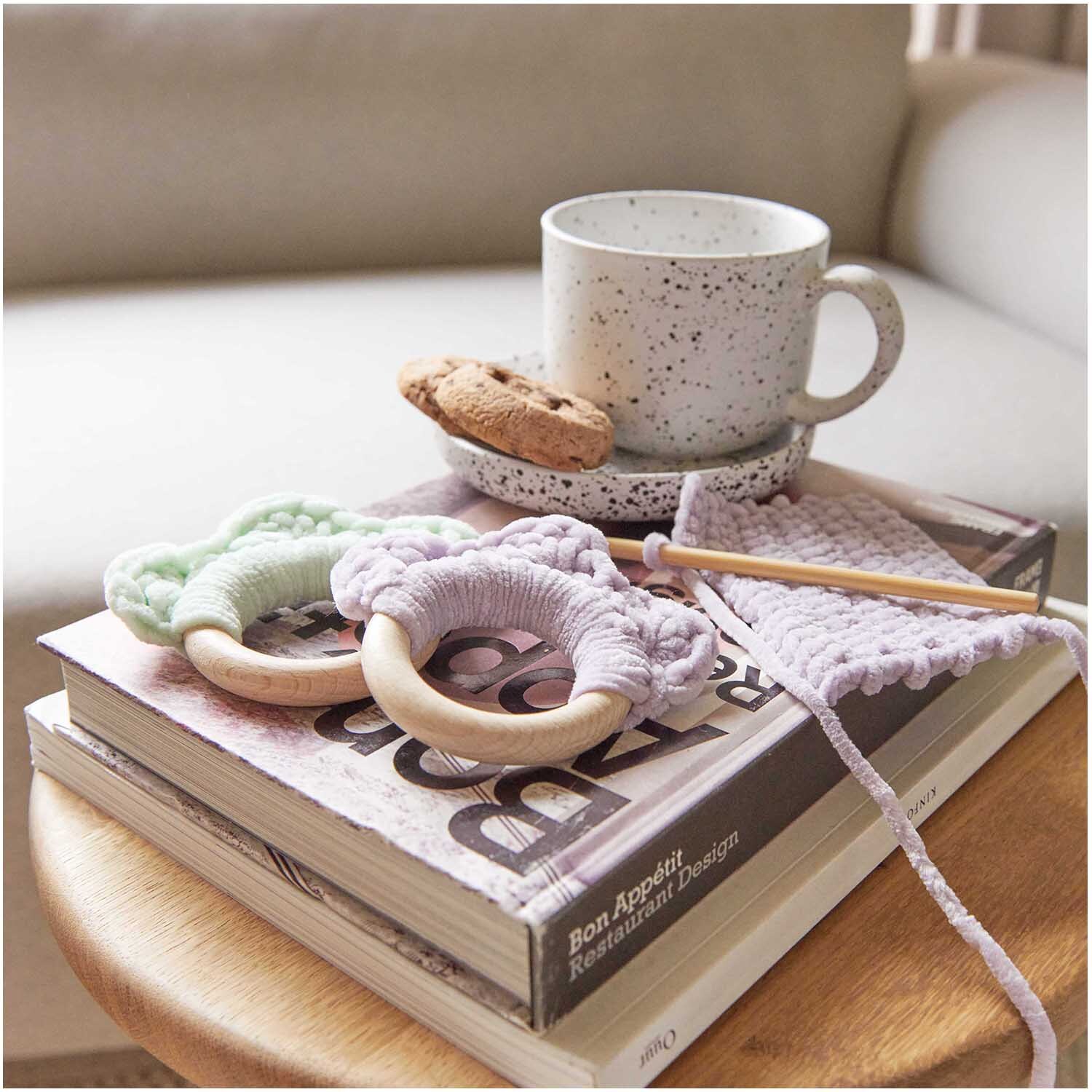 Creative Chenillove: Weiches Strickgarn in Flieder von Rico Design, auf einem Tisch mit Tasse und Keksen.
