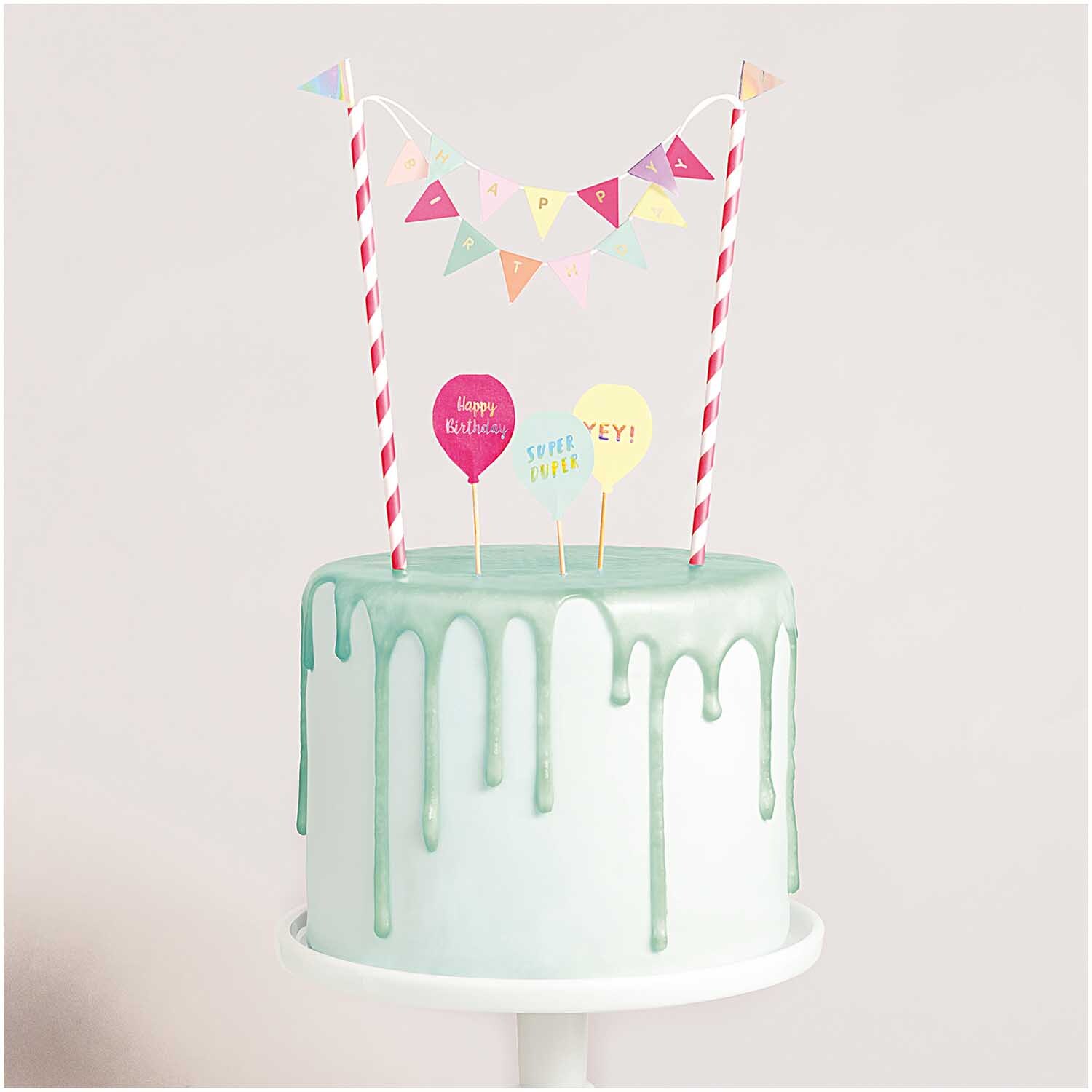 Kuchendekoration Happy Birthday pastell: Bunte Girlanden und Ballons auf einer Torte mit grünem Zuckerguss von Rico Design.