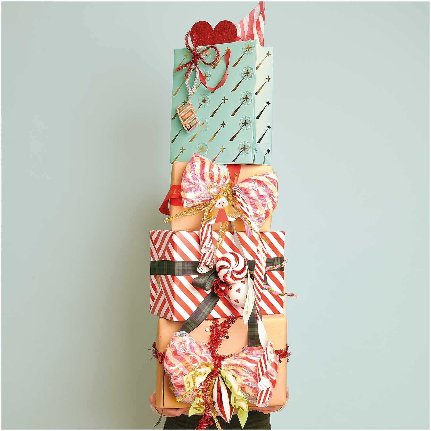 Paper Poetry Geschenkpapier mit rot-weißen Streifen, dekoriert mit Schleifen und Geschenken. Ideal für festliche Anlässe. Marke: Rico Design.