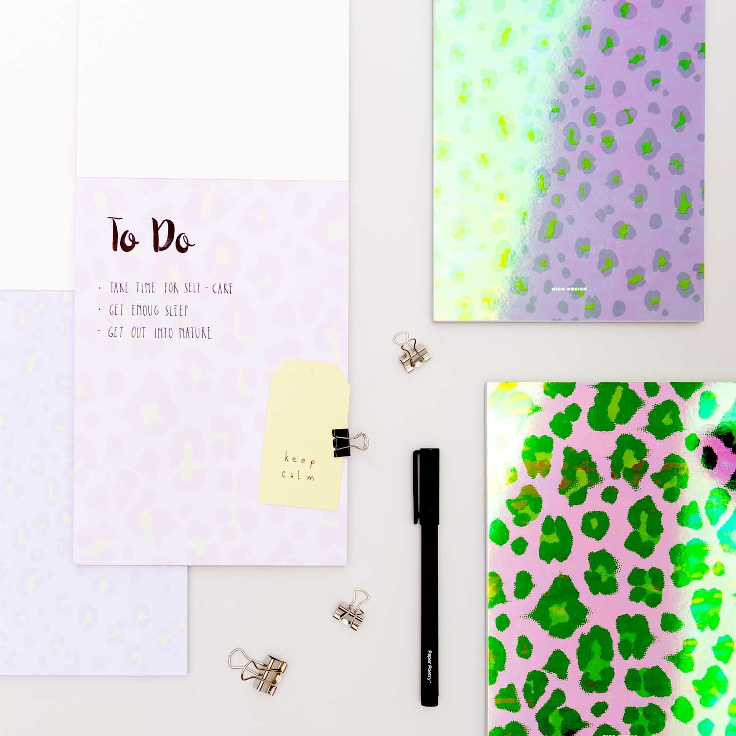 Paper Poetry Notizblock Acid Leo in Rosa, A5, 50 Blatt, 100g/m², mit buntem Leopardenmuster und Büroklammern.