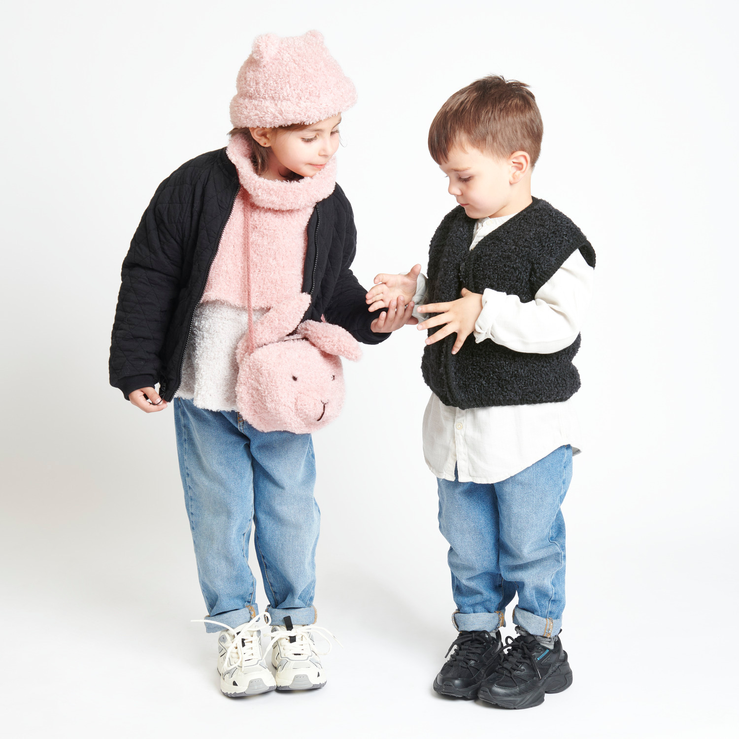 Creative Teddy: Zwei Kinder in modischer Kleidung, eines trägt rosa Accessoires, das andere schwarz.