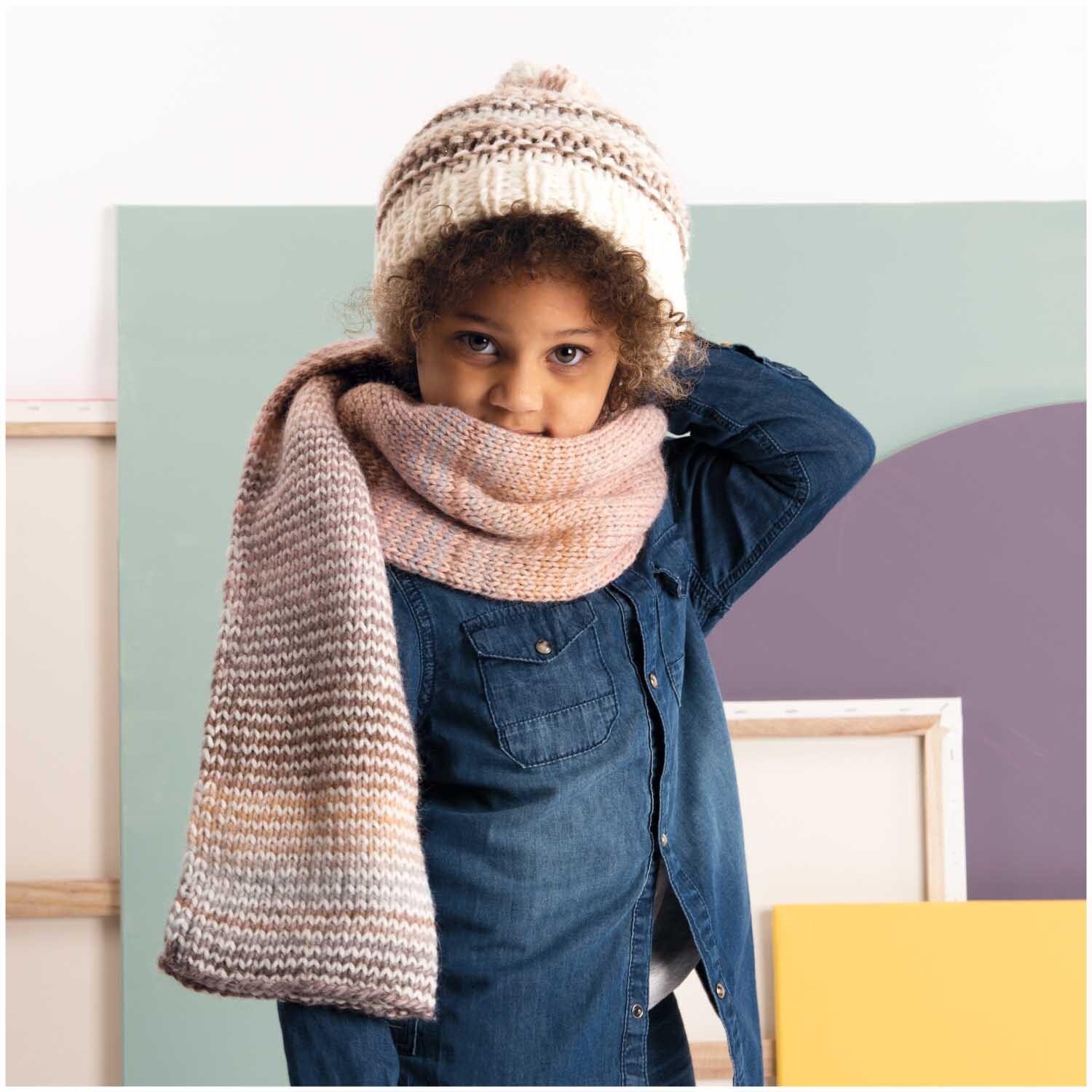 Essentials Alpaca Blend chunky: Kind trägt gestrickten Schal und Mütze in Creme- und Marinefarben von Rico Design.