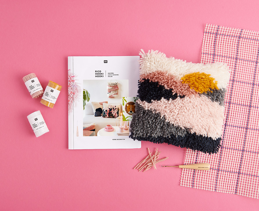 Kissen mit Knüpftechnik, Anleitungsheft und Zubehör. Flatlay von Produkten.