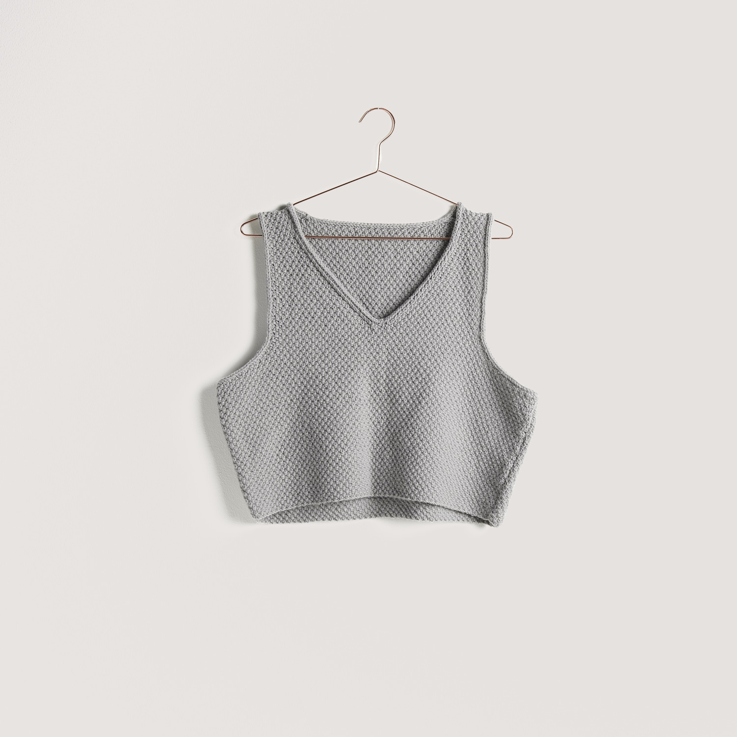 Strickset Top Modell 09a aus Vegan Cashmere, grau, von Rico Design, hängt auf einem Kleiderbügel.