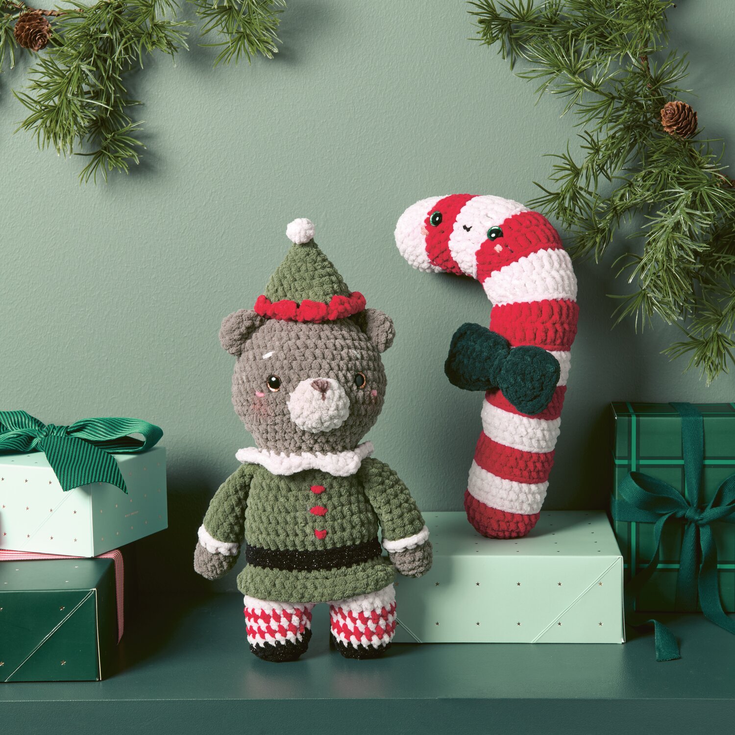 Chenillove Christmas: Niedlicher gehäkelter Bär in Oliv mit Zuckerstange, umgeben von Geschenken.