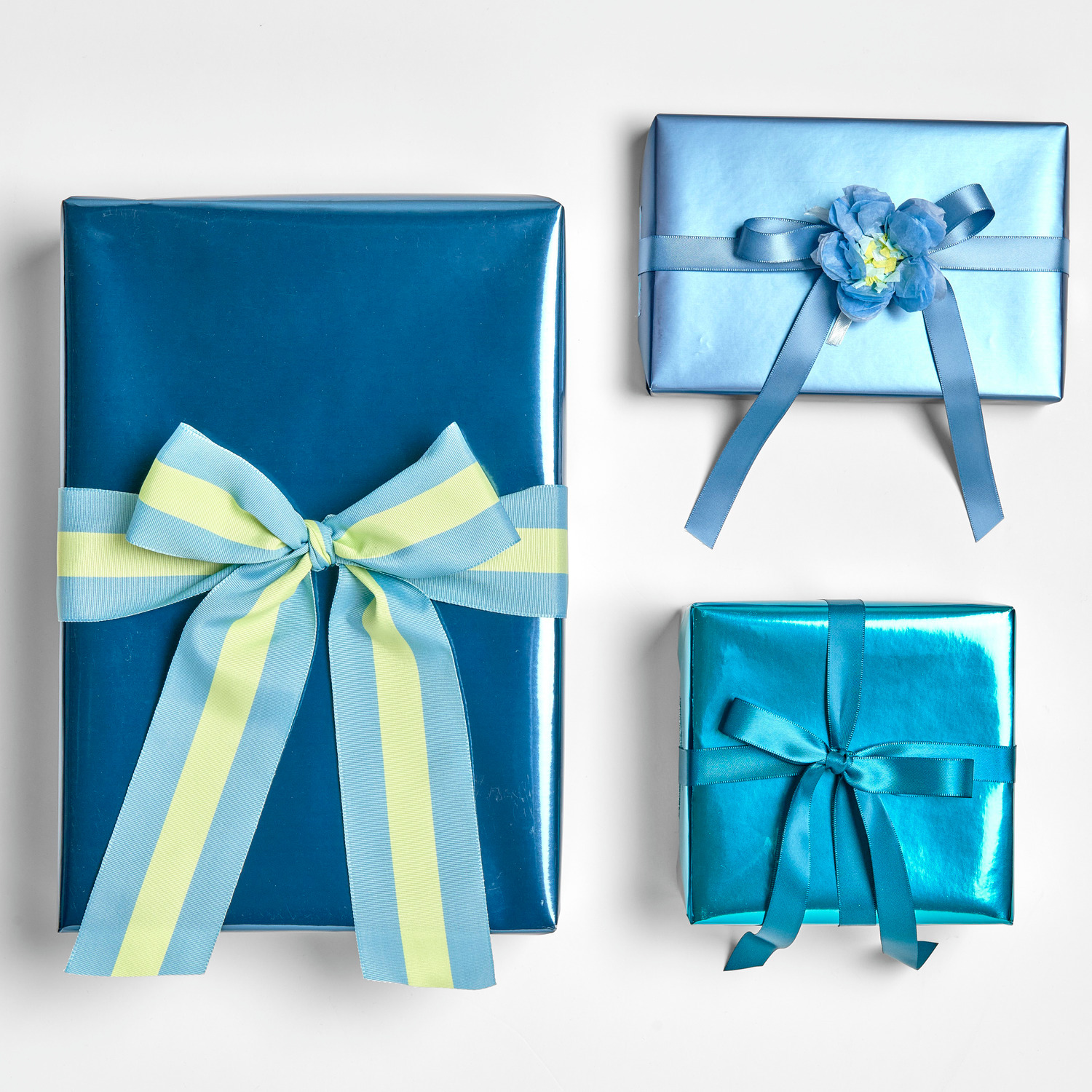 Geschenkpapier Metallic Matt: Drei in Blau verpackte Geschenke mit Schleifen, ideal für festliche Anlässe.