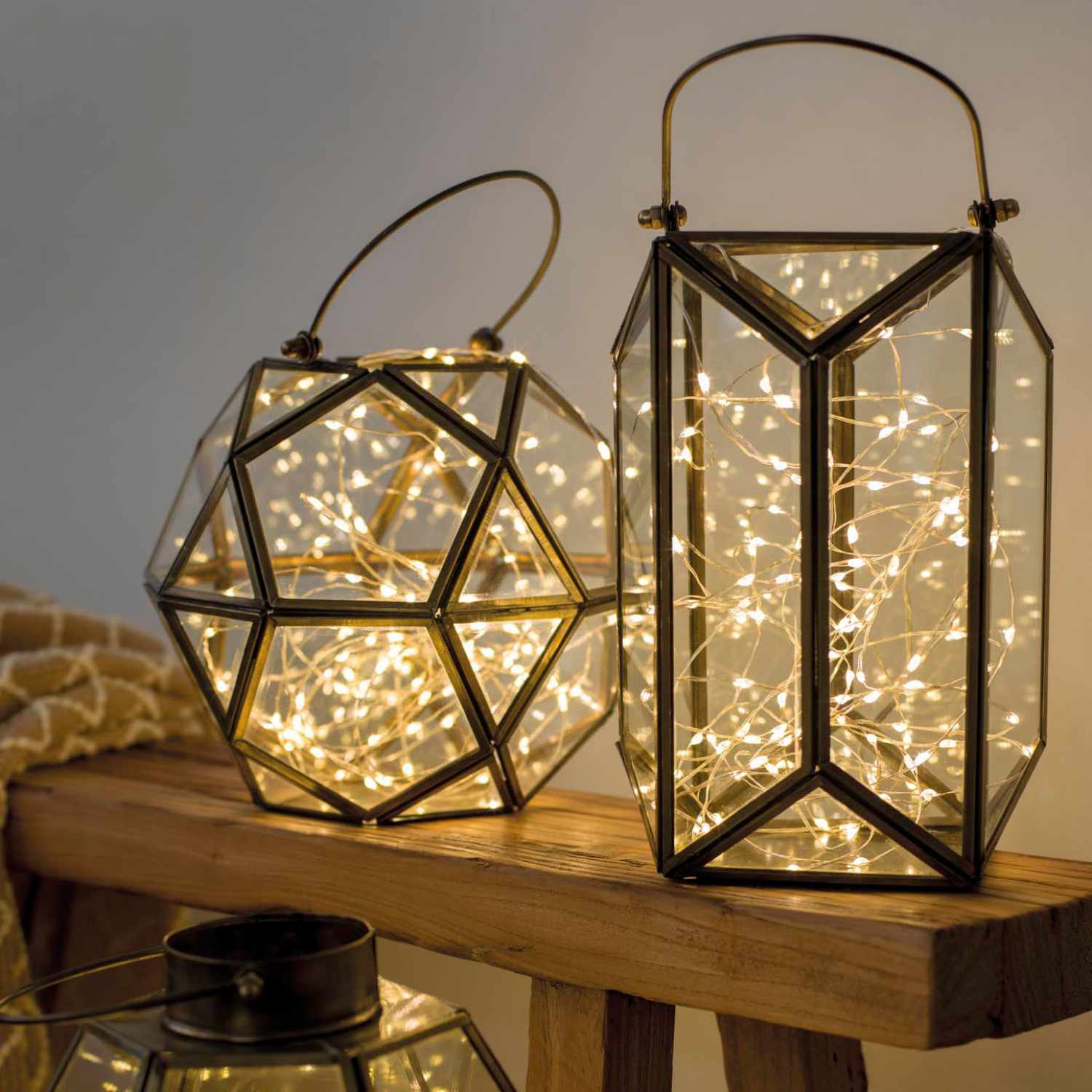 LED Micro Strang mit Timer batteriebetrieben warmweiß 95cm in dekorativen Laternen von Kaemingk auf einem Holztisch. Ideal für stimmungsvolle Beleuchtung.