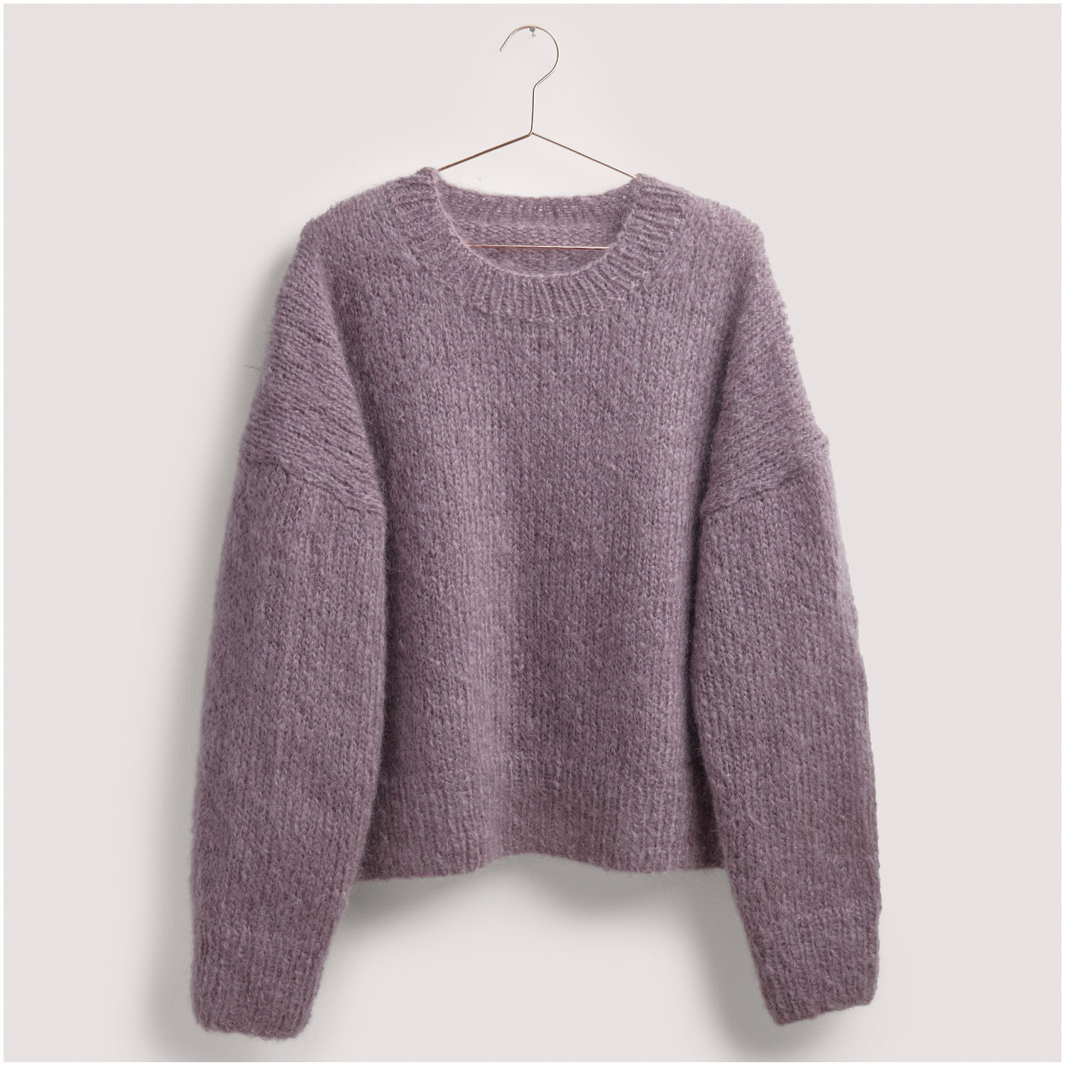 Strickset Pullover Modell 30 aus Die Neue Masche Nr. 8: Lila Pullover aus weichem Strickmaterial, hängend an einem Kleiderbügel.