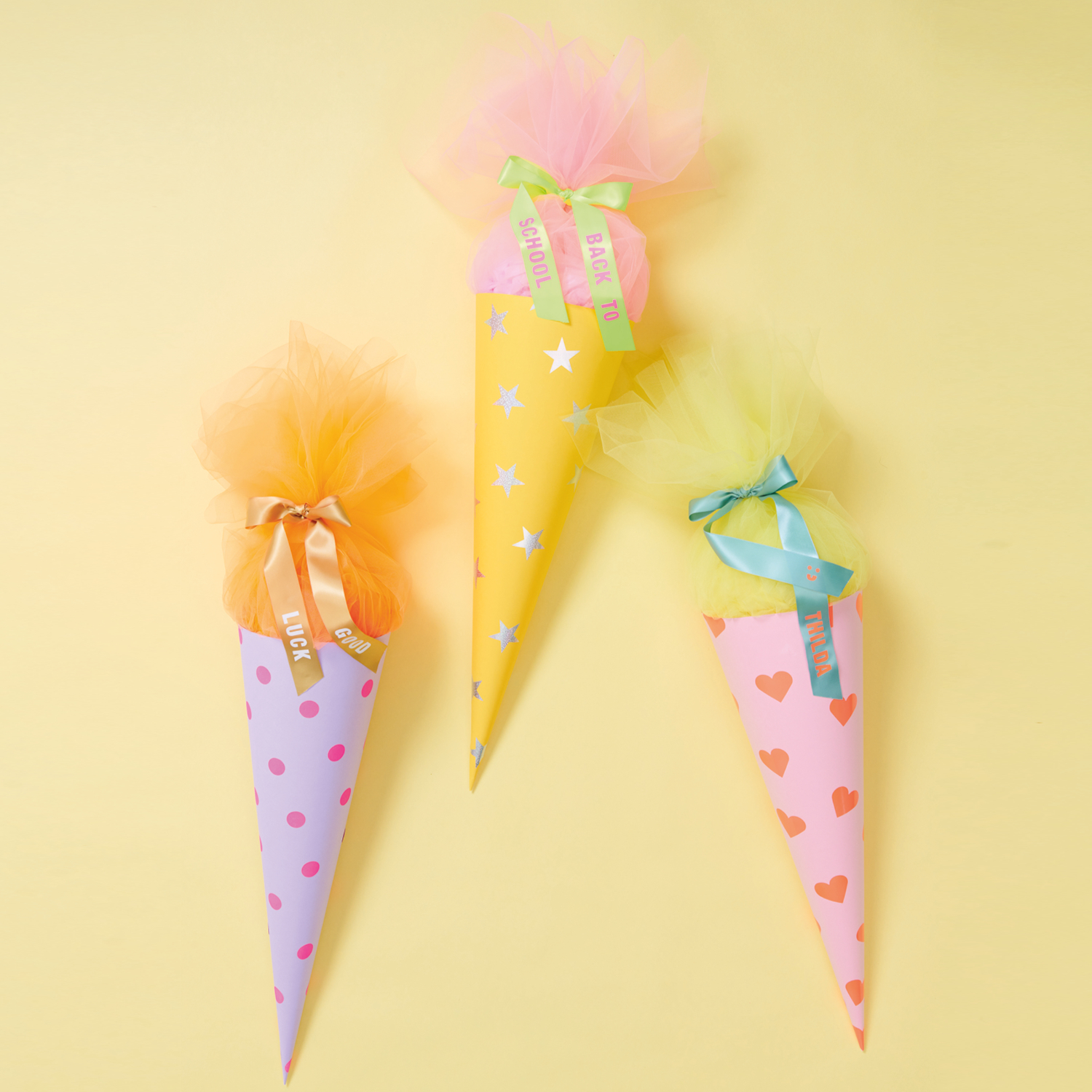 Bastelanleitung Schultüte mit Tüll und Stickern: Drei bunte Schultüten mit Tüll und Schleifen.