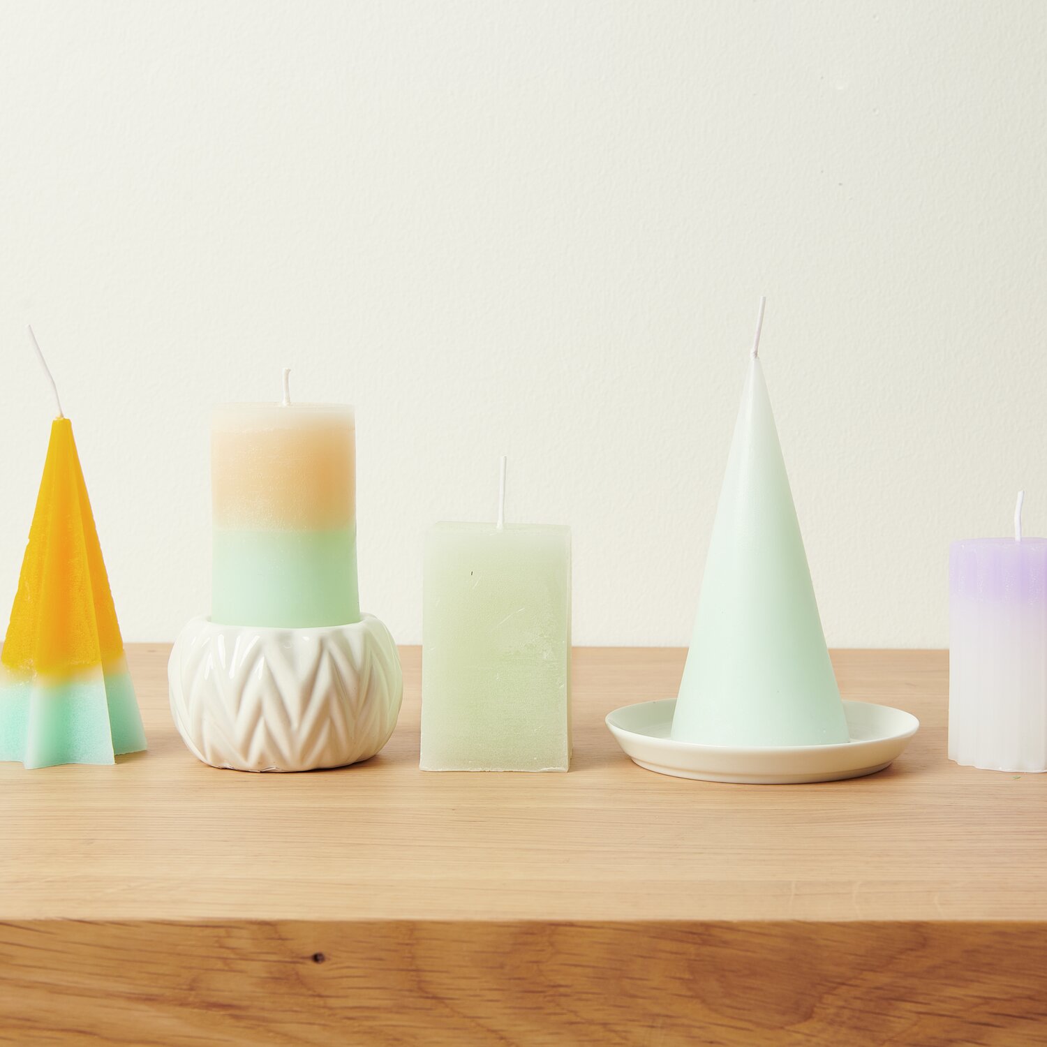 Kerzenwachs Granulat: Verschiedene bunte Kerzenformen auf Holzregal, ideal für DIY-Projekte.