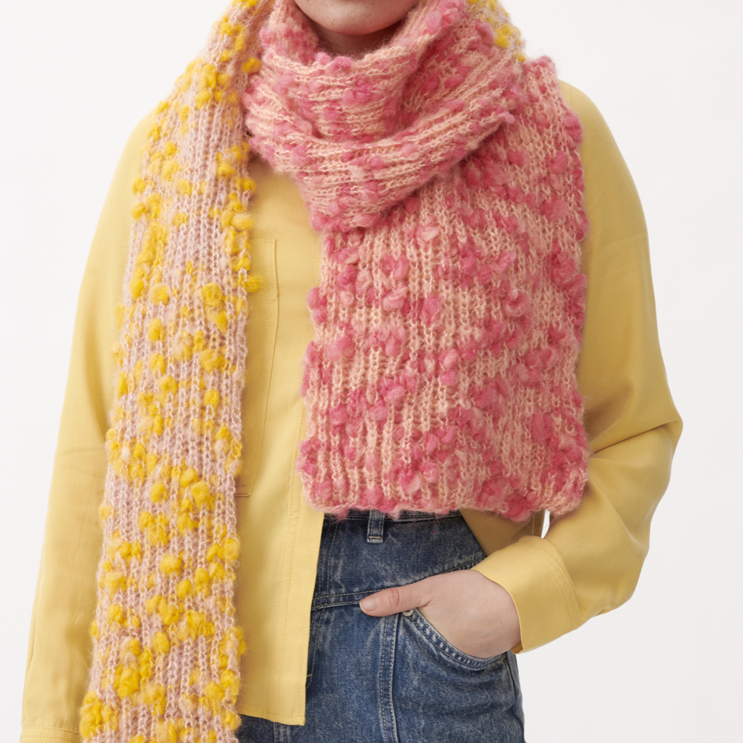 Strickanleitung Schal aus Fashion Alpaca Vibes: Frau trägt gelb-rosa Schal, gestrickt mit Alpaka-Wolle, über gelber Bluse.