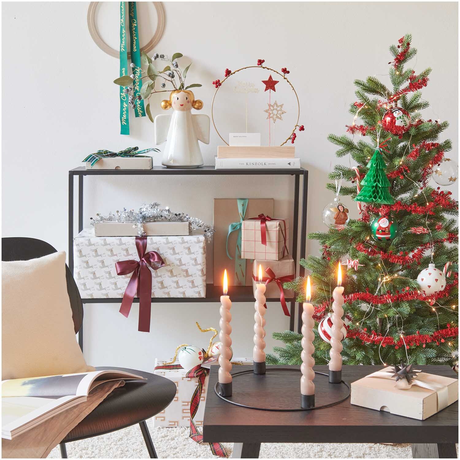 Glaskugel Engel handbemalt klar 8cm von Rico Design neben einem festlich dekorierten Weihnachtsbaum mit Kerzen und Geschenken.