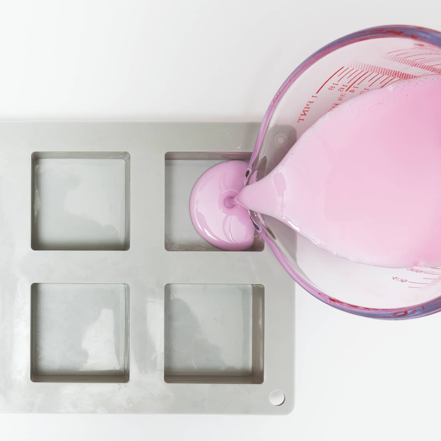 Geschmolzene rosa Seifenmaße wird in eine Gießform gegeben