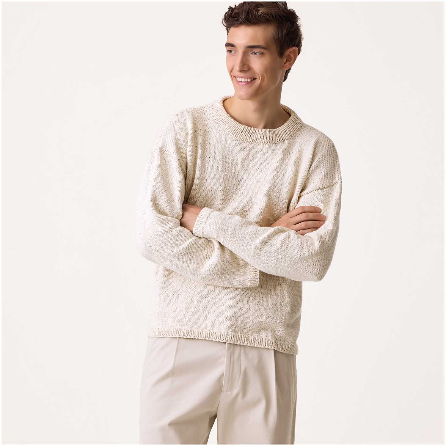 Luxury Organic Cotton Silk dk: Ein Mann trägt einen cremefarbenen Pullover von Rico Design, lächelnd mit verschränkten Armen.
