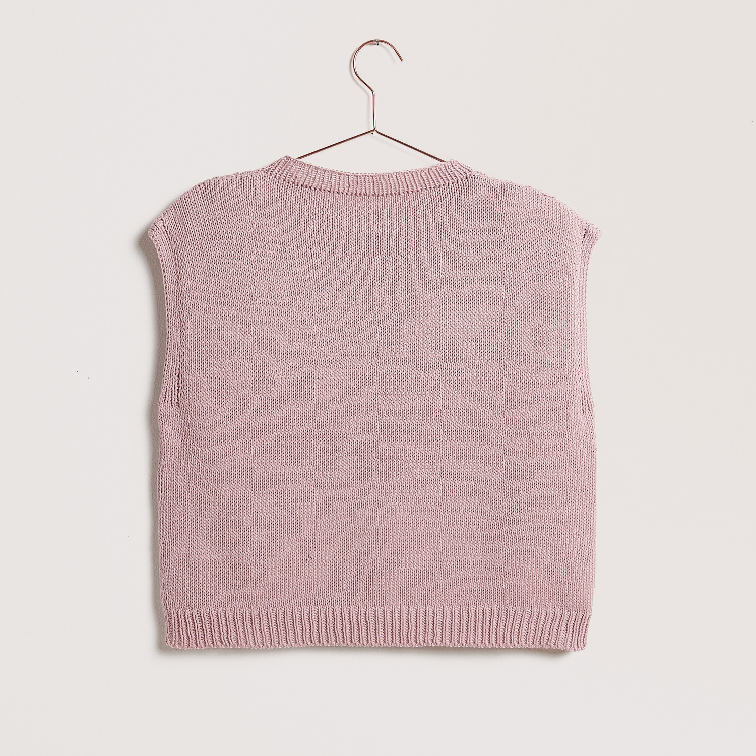 Die Neue Masche No. 12 Frühjahr-Sommer: Ein gestrickter Pullover in zartem Rosa auf einem Kleiderbügel. Ideal für die Saison.