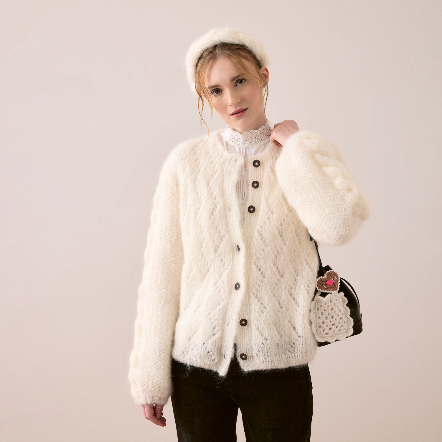 Strickset Jacke Modell 01a aus Trachtenbuch I mog di: Frau trägt cremefarbene Strickjacke und Haarreifen von Rico Design, kombiniert mit Tasche.