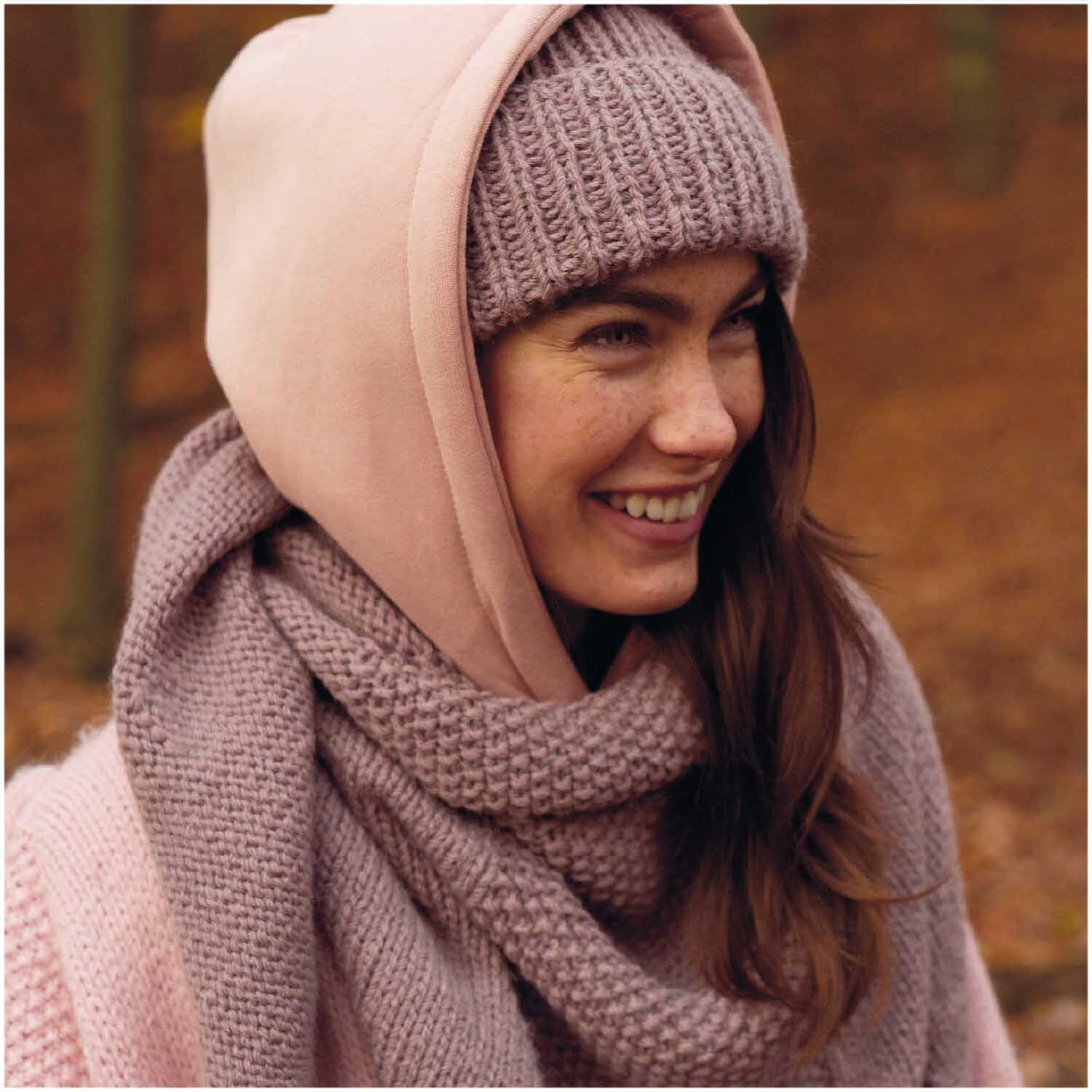 Essentials Alpaca Twist Chunky: Frau in gestricktem Schal und Mütze im Wald, warmes Mauve, 50g 65m. Ideal für kühle Herbsttage.