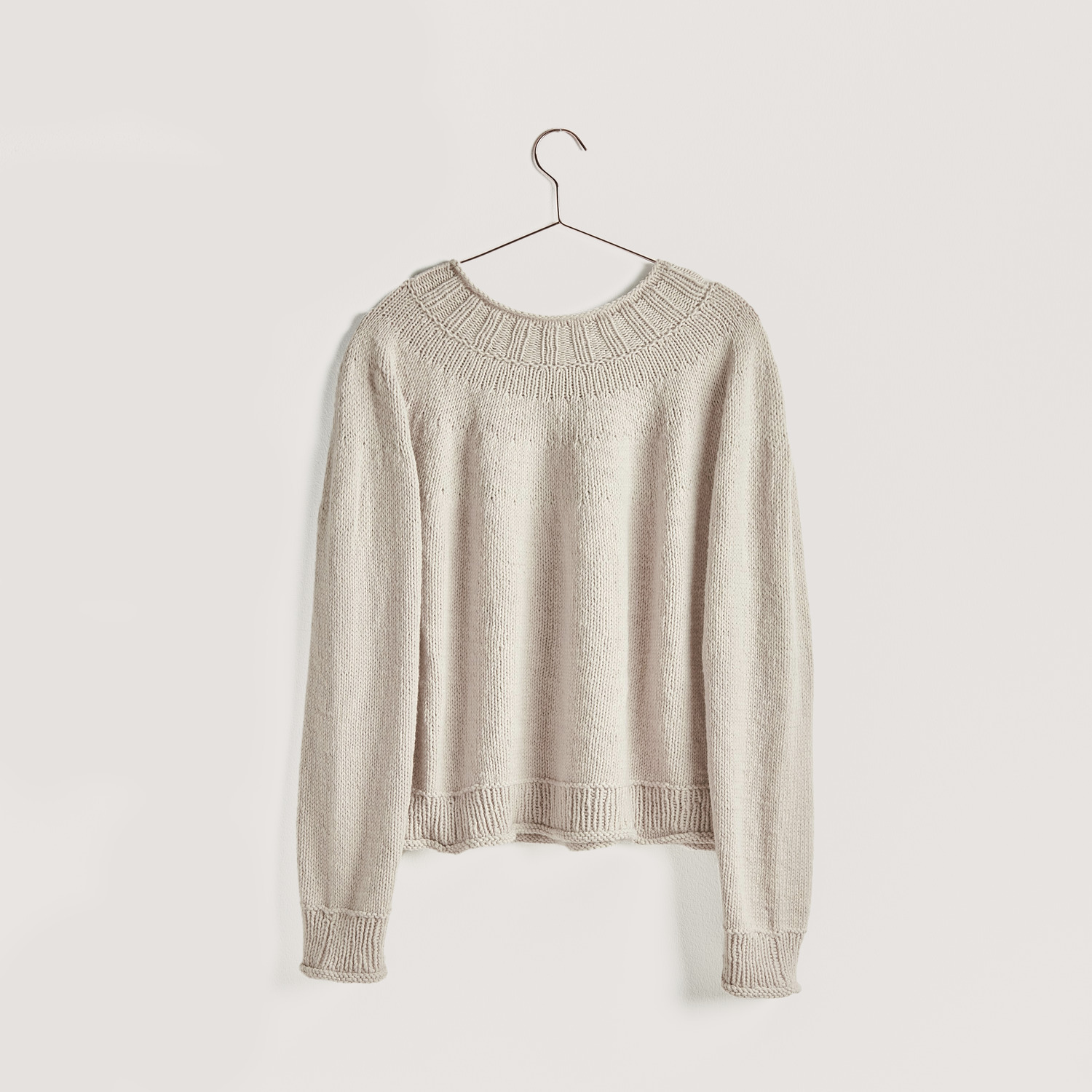 Strickset Pullover Modell 03a aus Vegan Cashmere in Beige, hängend auf einem Kleiderbügel. Ideal für nachhaltige Modeprojekte.