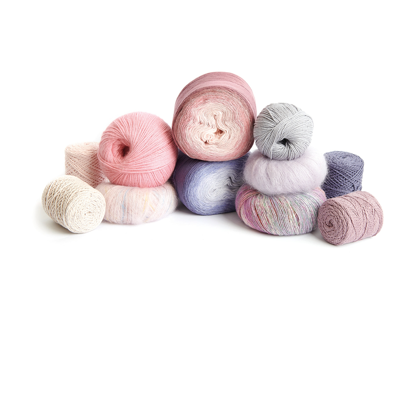 Stapel mit Garnknäueln in Creme, Rosa und Lila Tönen