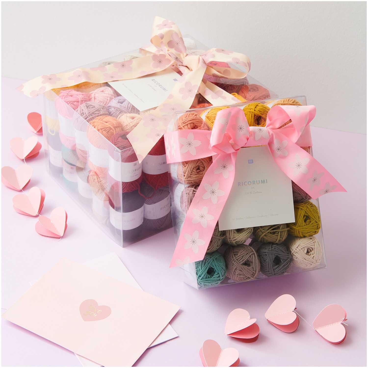Creative Ricorumi dk Set Limited: Geschenkbox mit buntem Garn von Rico Design, dekoriert mit rosa Schleifen und Herzen.