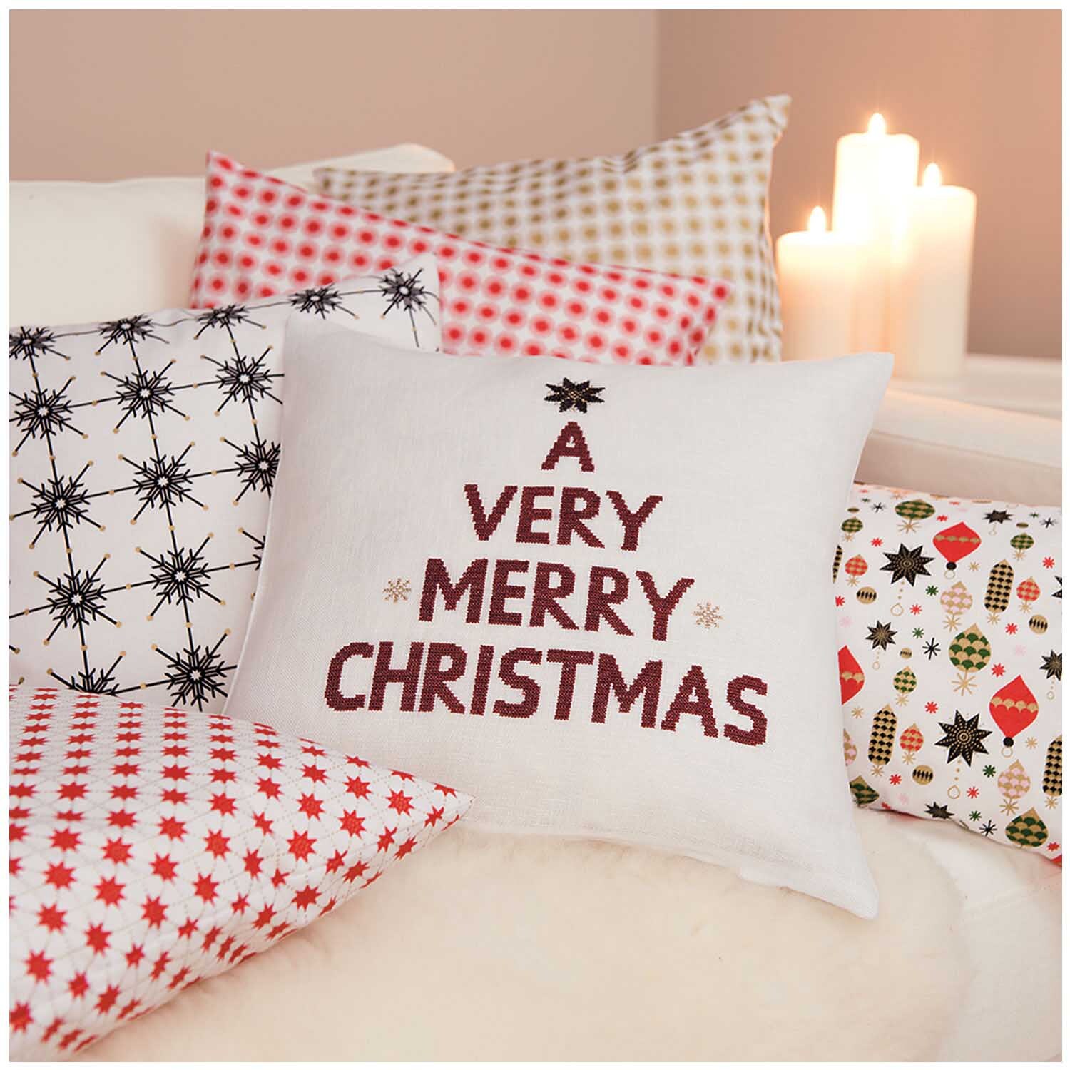 Stoff Eiskristall schwarz-gold 50x140cm von Rico Design, dekoriert mit weihnachtlichen Kissen und Kerzen im Hintergrund.