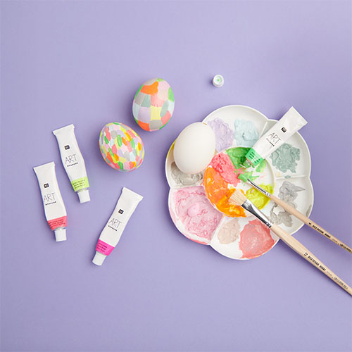 Bunt bemalte Ostereier mit dazugehörigen Farben und Malpalette mit Pinsel. Flatlay von Produkten.