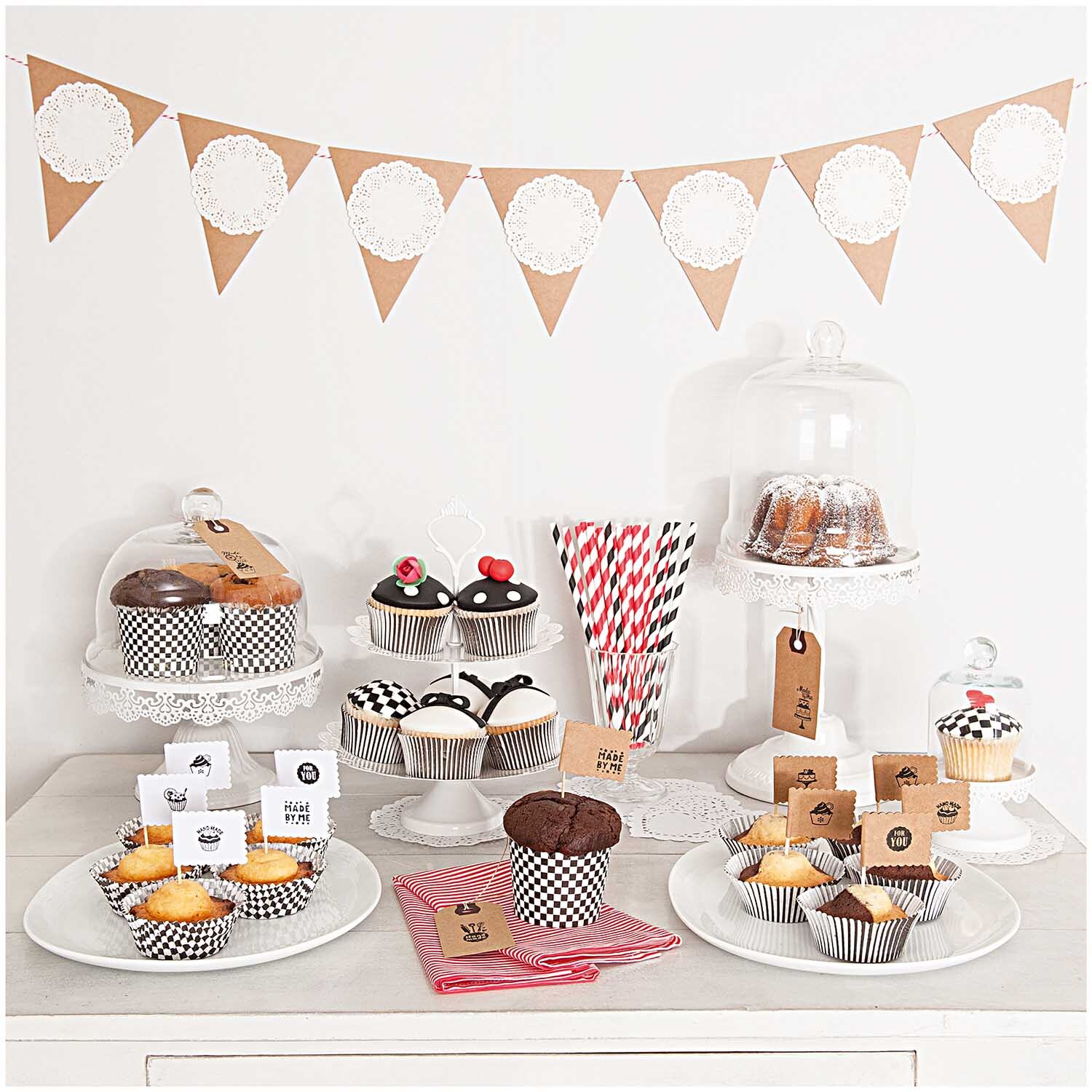 Paper Poetry Geschenkanhänger aus Kraftpapier dekorieren eine festliche Kuchentafel mit Muffins und Kuchen unter Glasglocken.