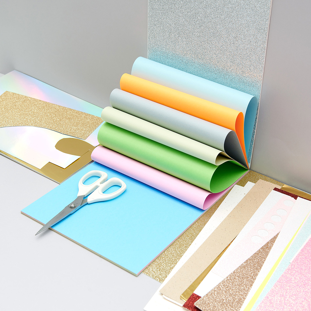 Verschiedenstes Bastelpapier und Bastelkarton aufgefächert. Fotosetting graue Ecke.