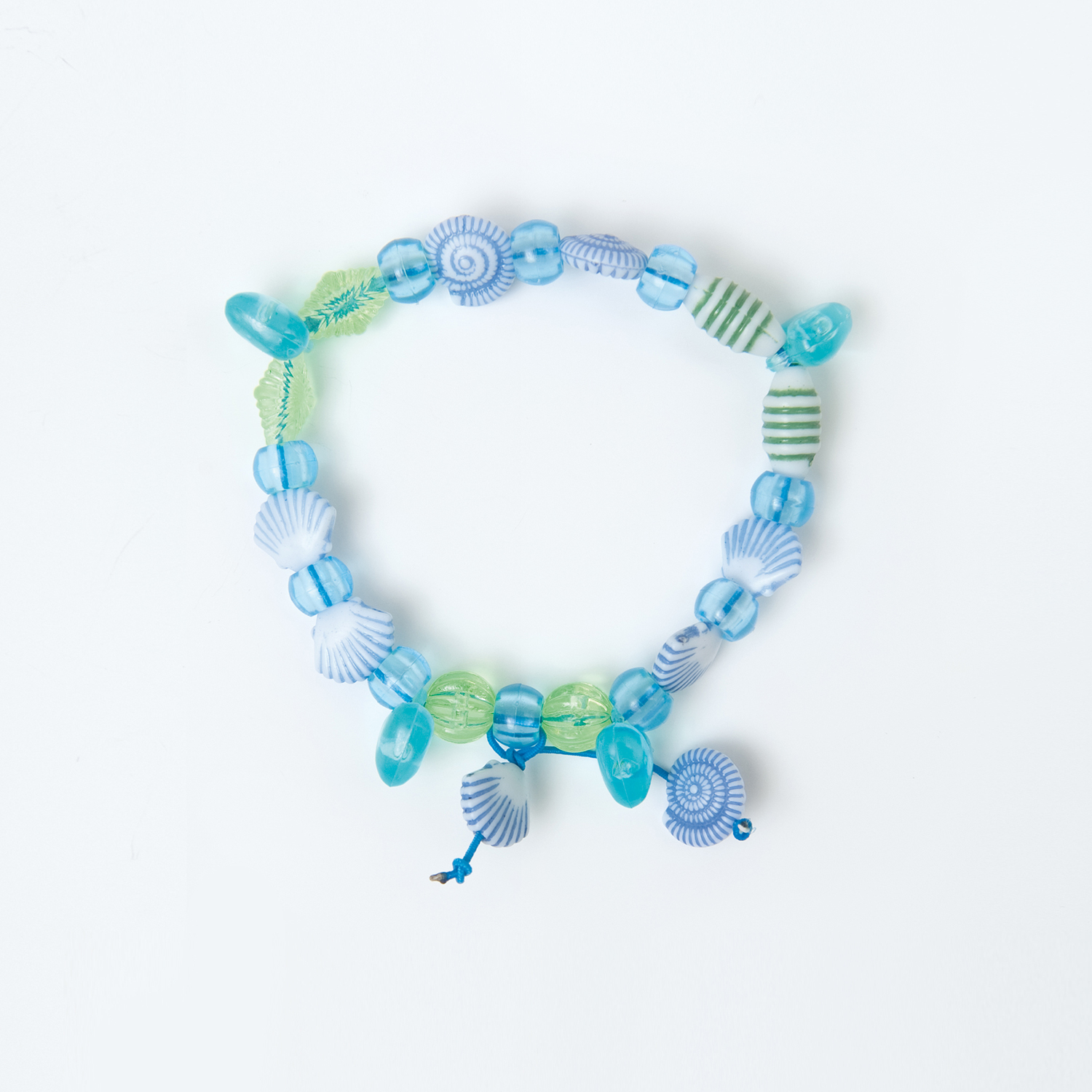 Anleitung DIY Perlenset Beads Muschelarmband basteln: Buntes Armband mit blauen und grünen Muschelperlen auf weißem Hintergrund.