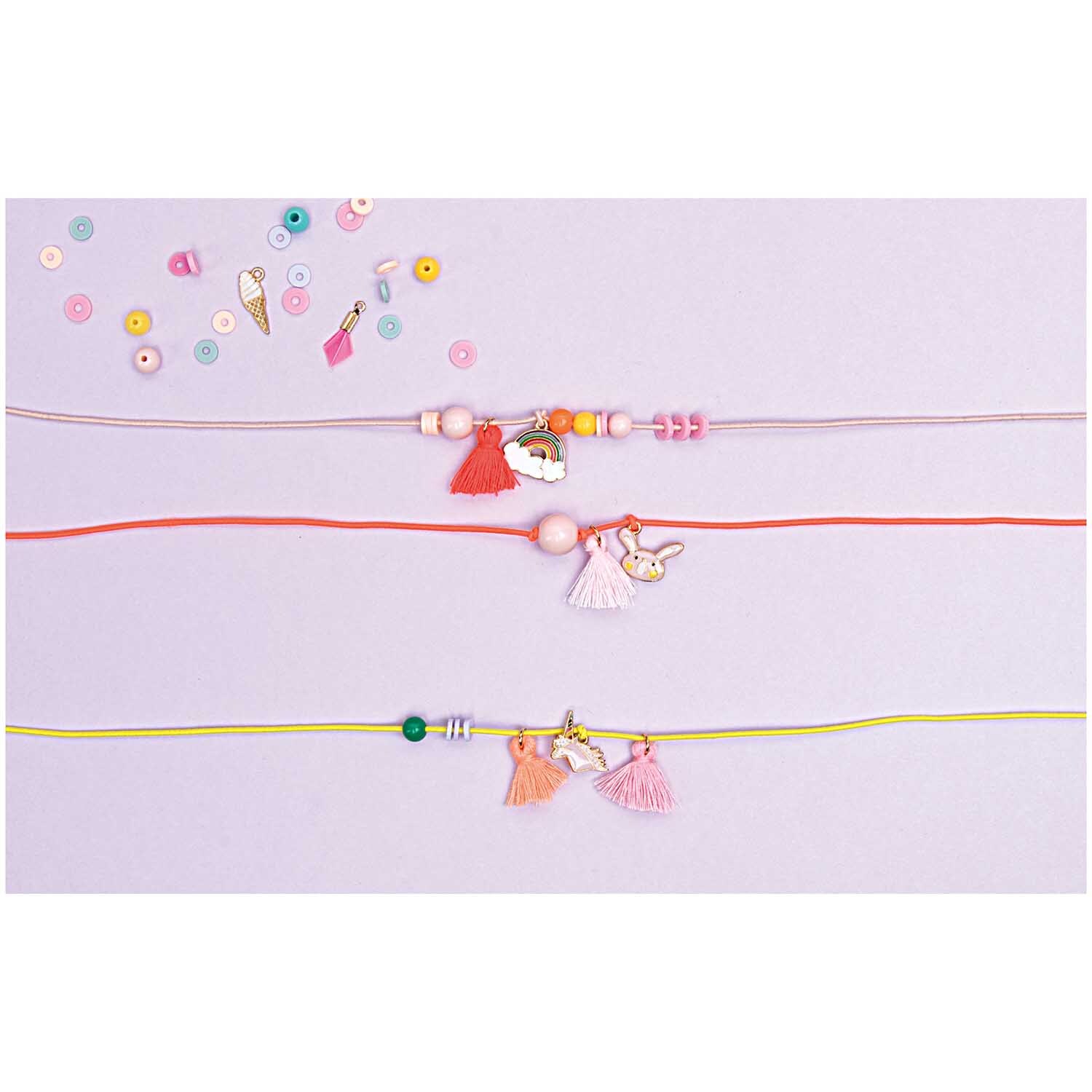 Anhänger Quasten Mix candy 5 Stück von Rico Design auf pastellfarbenem Hintergrund mit bunten Perlen und Charms.
