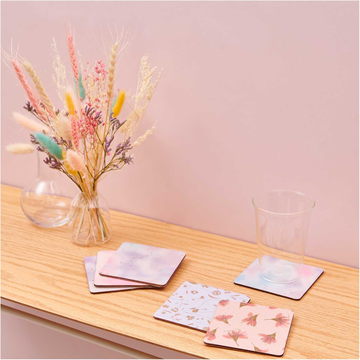 Paper Poetry Paper Patch Papier in sanften Rosa- und Violetttönen, dekoriert mit einem Glas und Trockenblumen auf einem Holztisch.