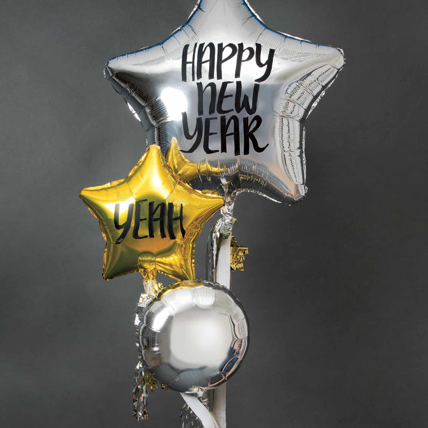 Anleitung Folienballon als Silvesterdeko: Drei glänzende Ballons in Sternform, einer silbern mit "Happy New Year", einer gold mit "Yeah".