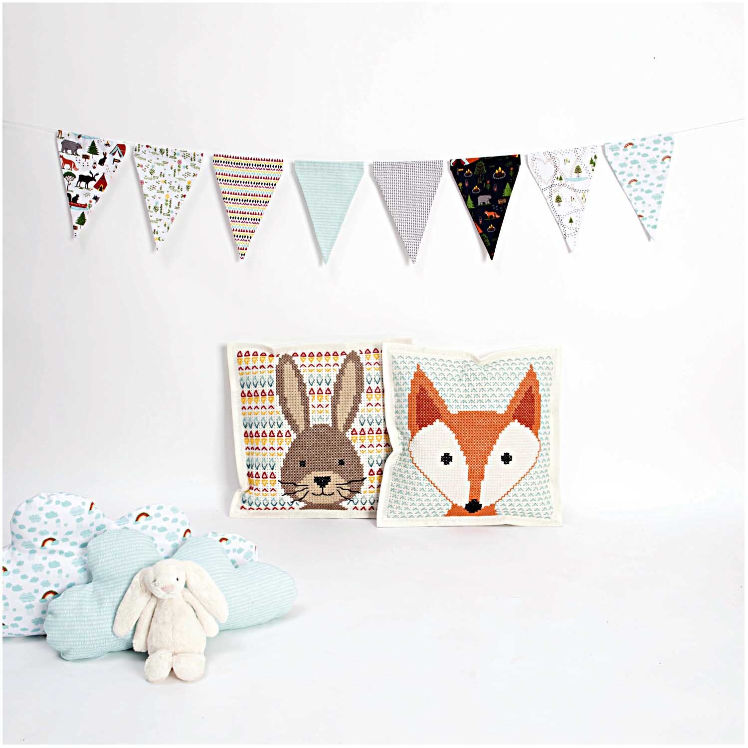 Filzkissen zum Besticken Hase 42x42cm von Rico Design, dekoriert mit bunten Wimpeln und Kissen in Tiermotiven.