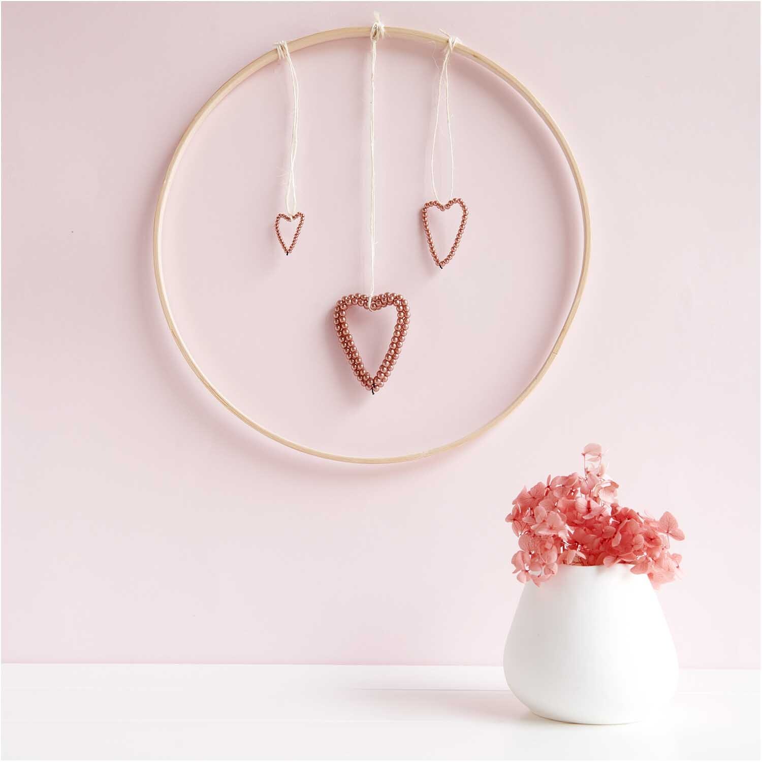 Perlenhänger Herz groß rosegold: Drei herzförmige Anhänger in einem Ring, dekoriert in Rosa, von Rico Design.