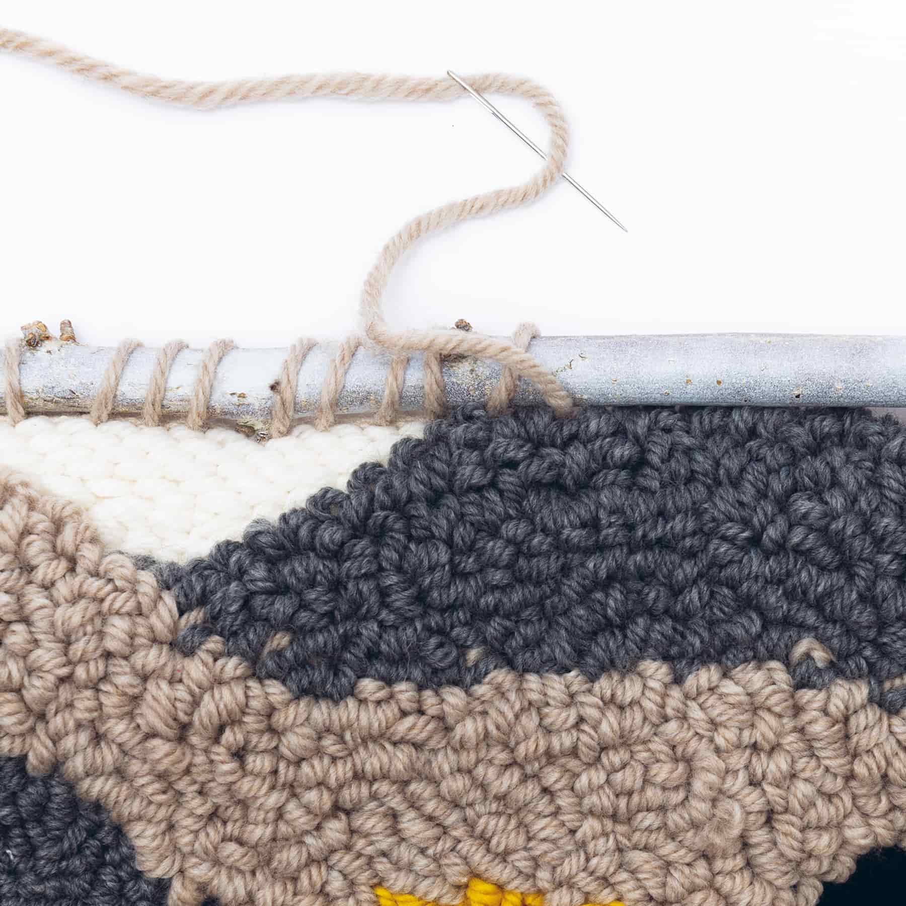 Punch Needle Modell wird mit Wollfaden an Stange genäht