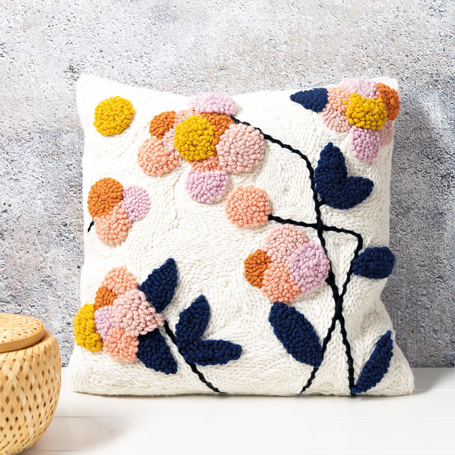 Anleitung florales Punch Needle Kissen mit buntem Blumenmuster auf weißem Hintergrund, dekorativ platziert.