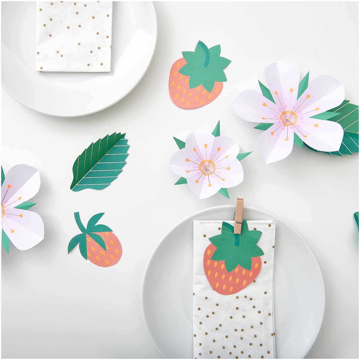 Paper Poetry Papierdekoration mit Erdbeeren und Blüten auf einem gedeckten Tisch, ideal für sommerliche Anlässe.