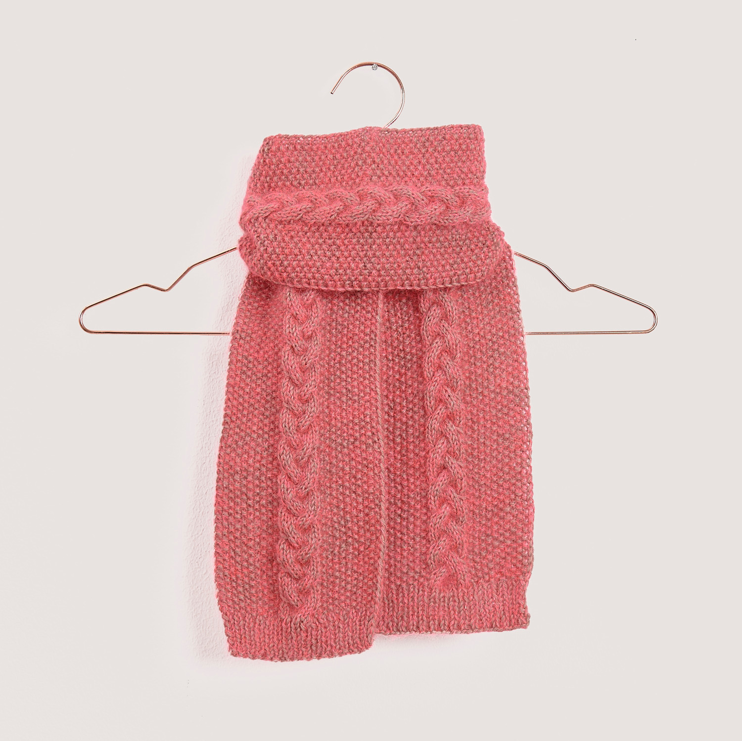 Strickset Mini Tuch Modell 07: Rosa Schal mit Zopfmuster, präsentiert auf einem Kleiderbügel.