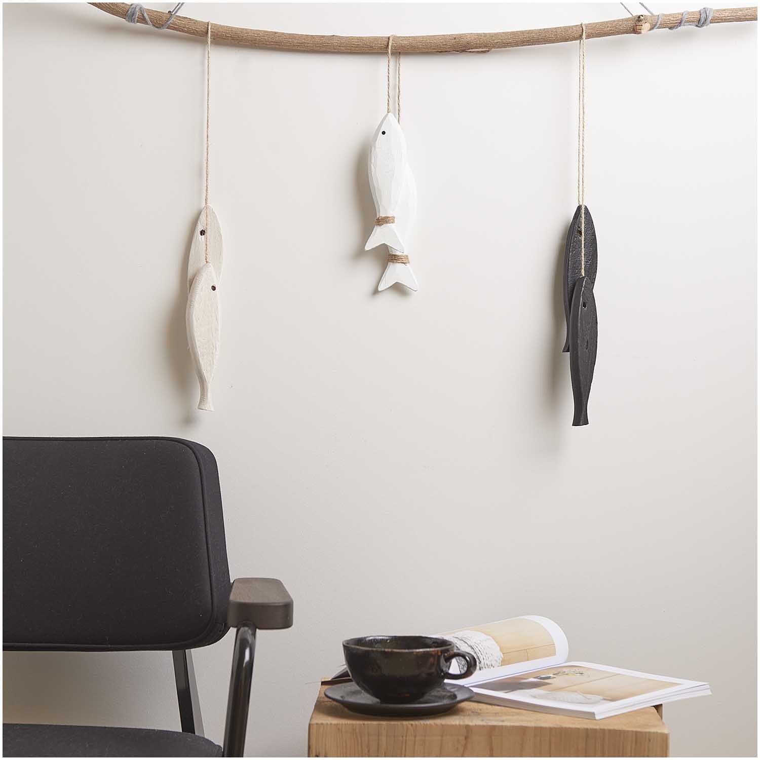 Holzhänger Fische mit Juteband weiß 19x5cm, dekorativ an Ast hängend, neben schwarzem Stuhl und Holztisch mit Tasse und Magazin.