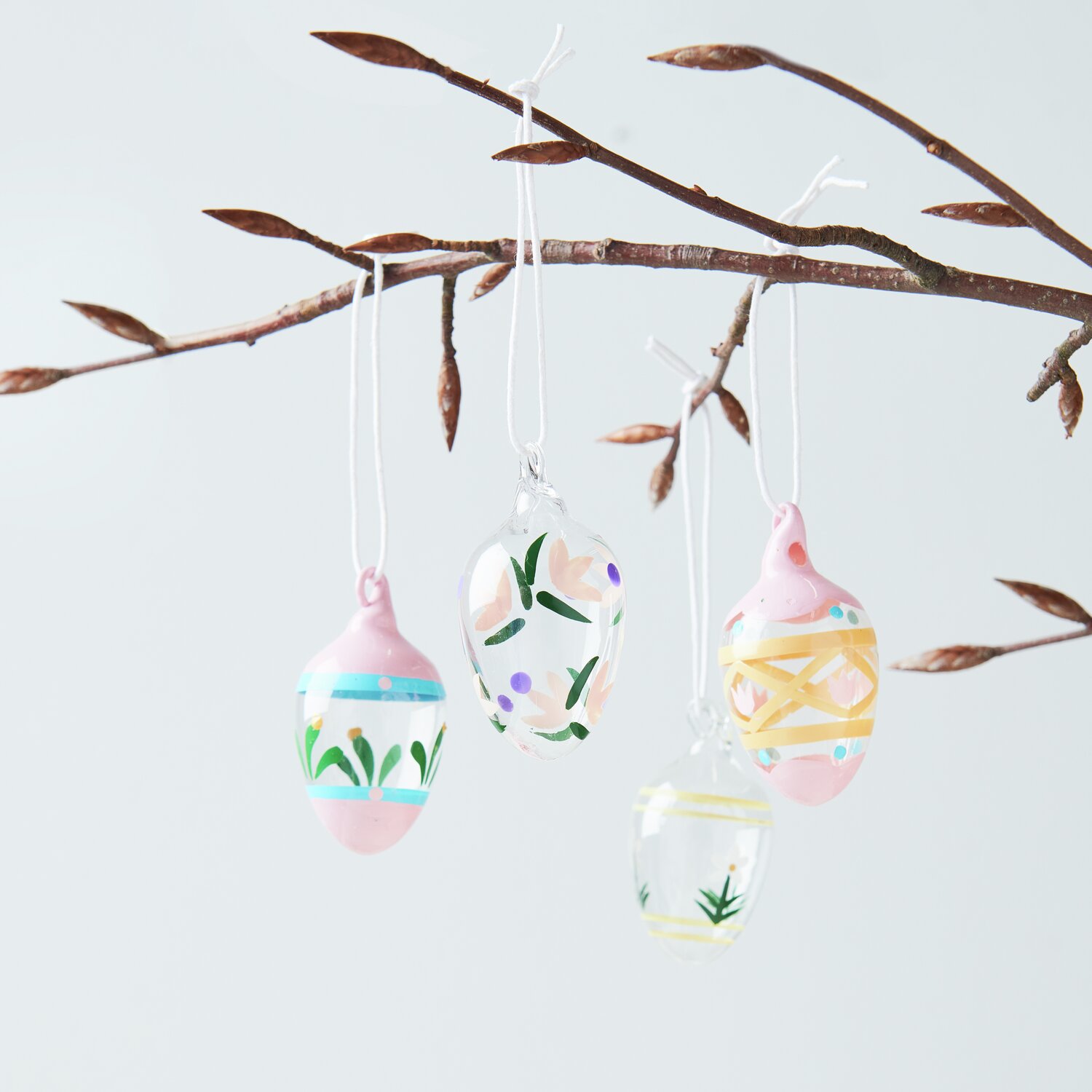 Glas Eier Blumen handbemalt: Vier handbemalte Glaseier mit floralen Mustern an einem Ast hängend. Größe Ø3x6cm, 4-teilig von Rico Design.