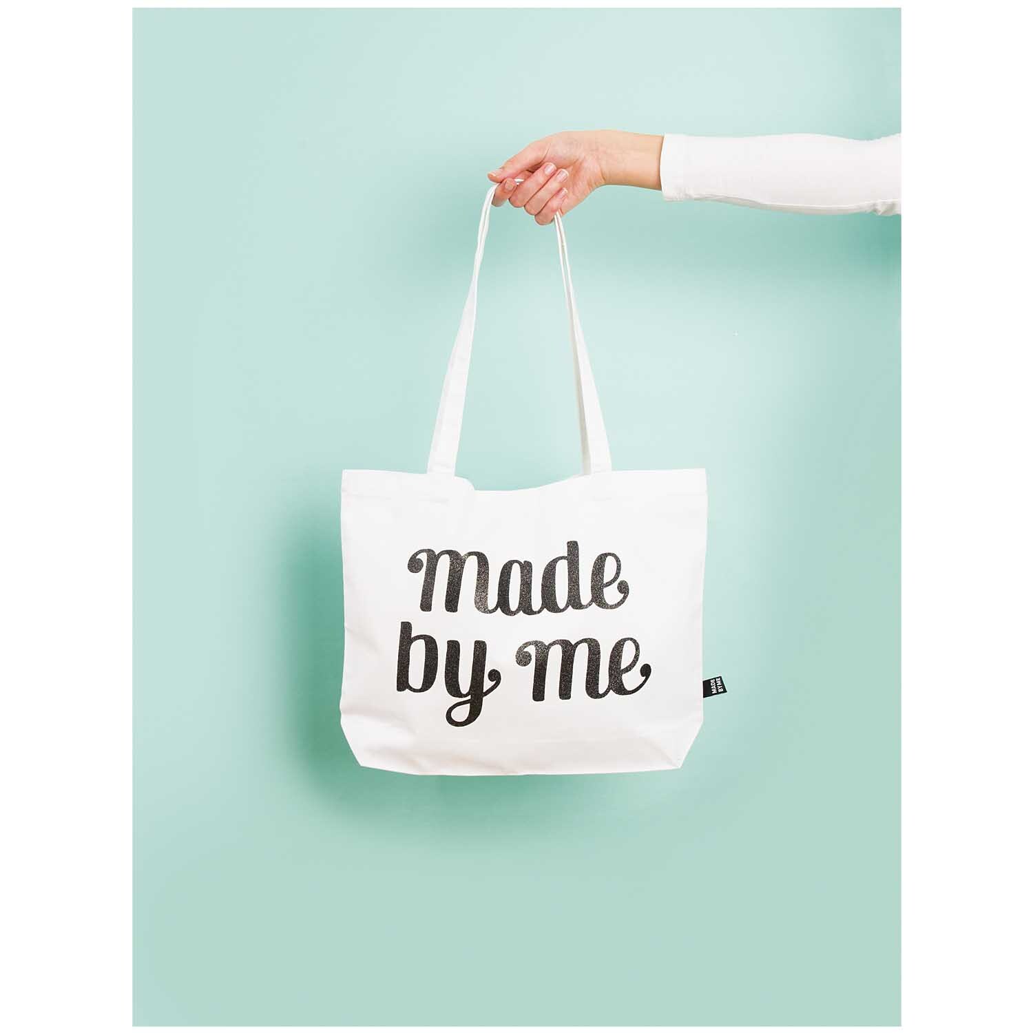 Tasche mit langen Henkeln, gehalten von einer Hand vor mintgrünem Hintergrund, von Rico Design.