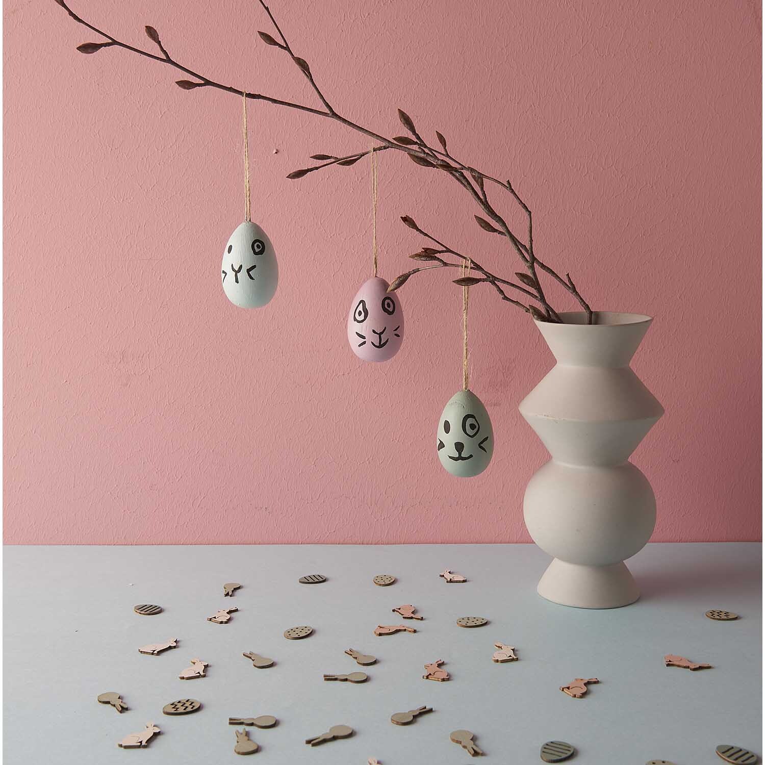 Holzeier zum Hängen 3 Stück von Rico Design in einem modernen Raum mit rosa Wand und dekorativem Ast.