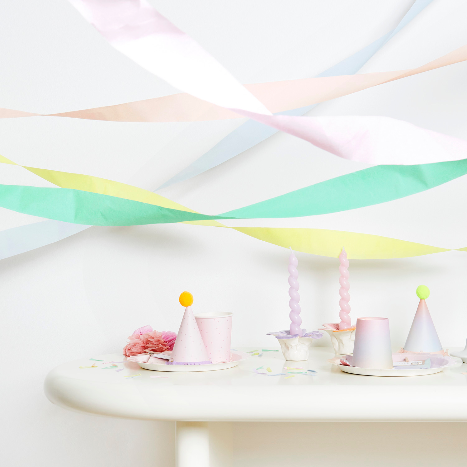 Kreppbänder extra breit Regenbogen Pastell Mix dekorieren einen Tisch mit Partyhüten und Kerzen.