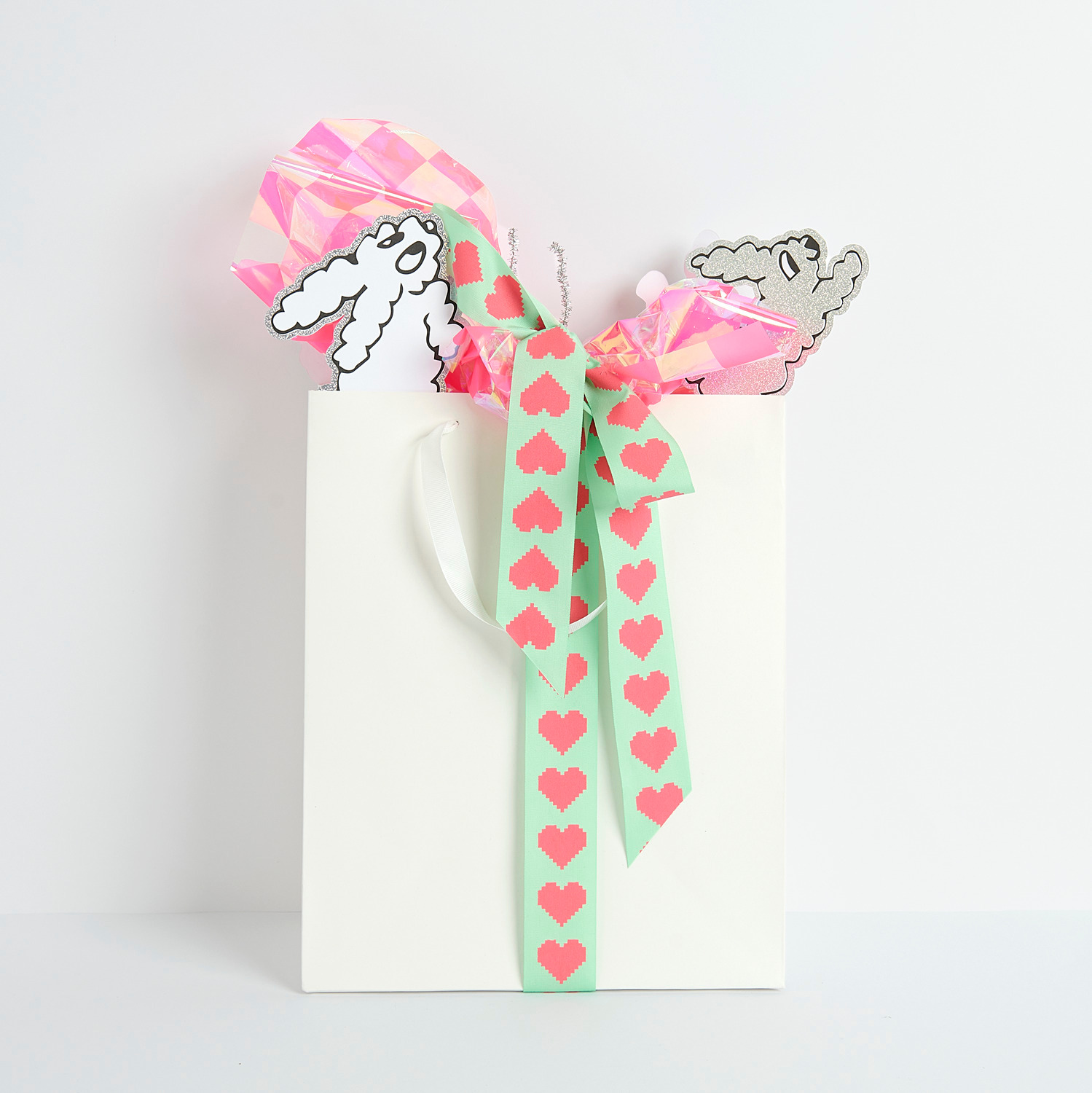 Paper Poetry Geschenktüte mit pinker Schachbrett-Geschenkfolie und Hasen-Pickern, verziert mit Herzband.