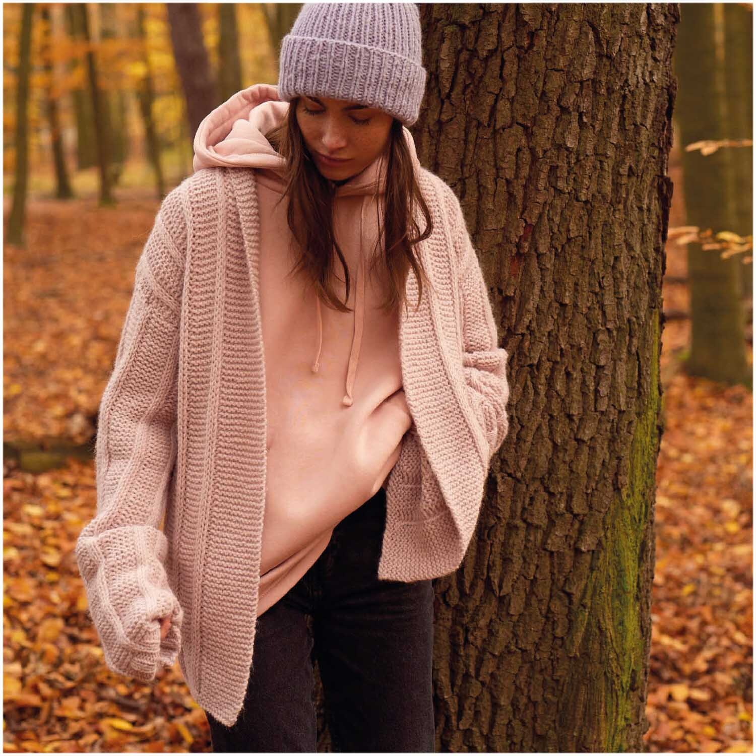 Essentials Alpaca Twist Chunky: Frau im Herbstwald trägt fliederfarbenen Strickcardigan von Rico Design.