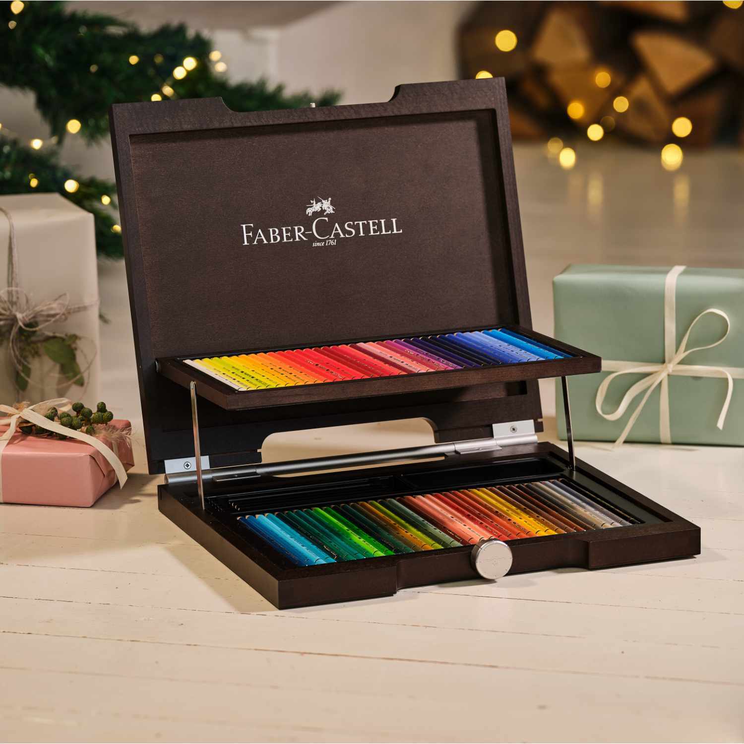 Polychromos Farbstifte Holzkoffer, 72-teilig, von Faber Castell, geöffnet auf einem Tisch mit Geschenken.